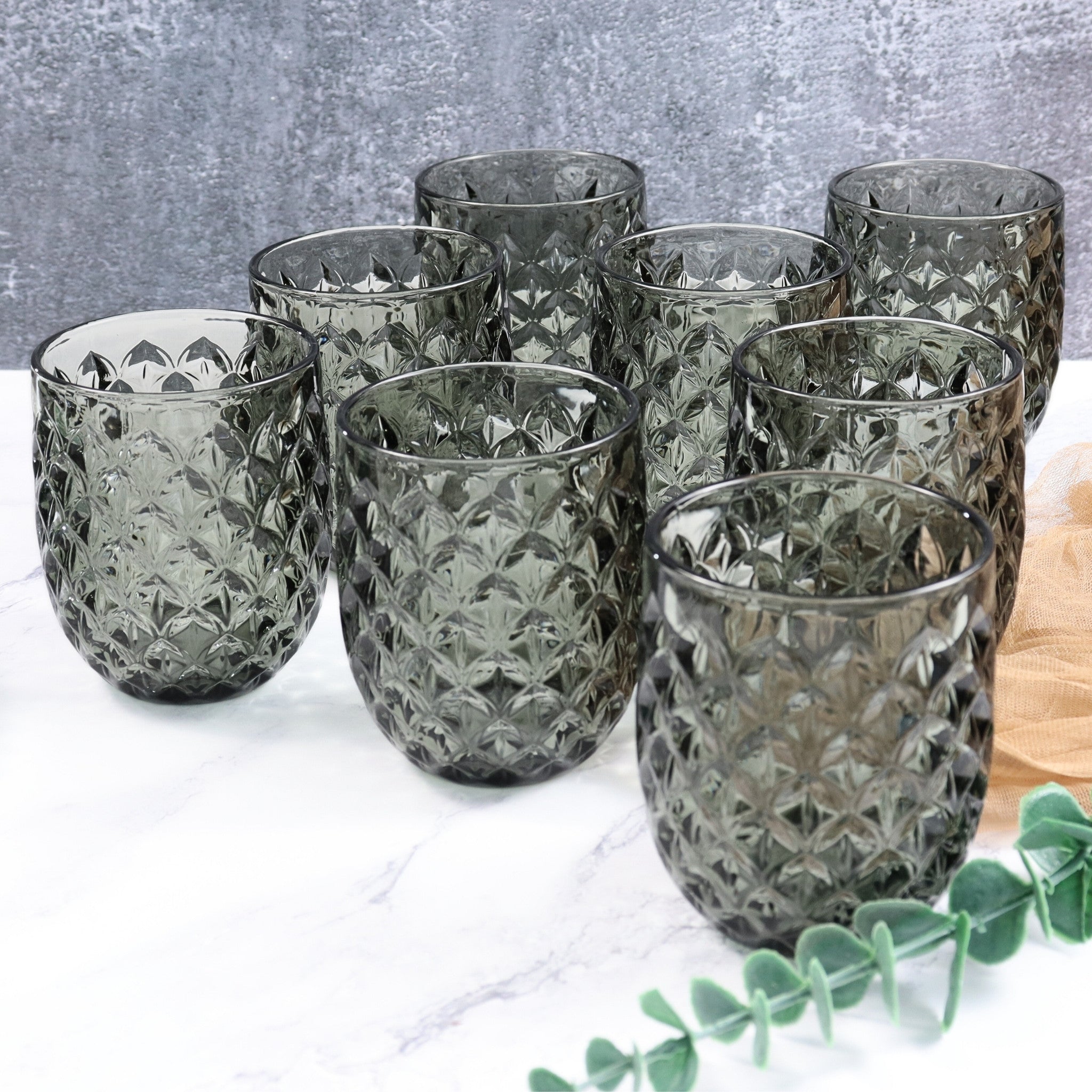Set of eight textured glass tumblers on a white surface with a gray background