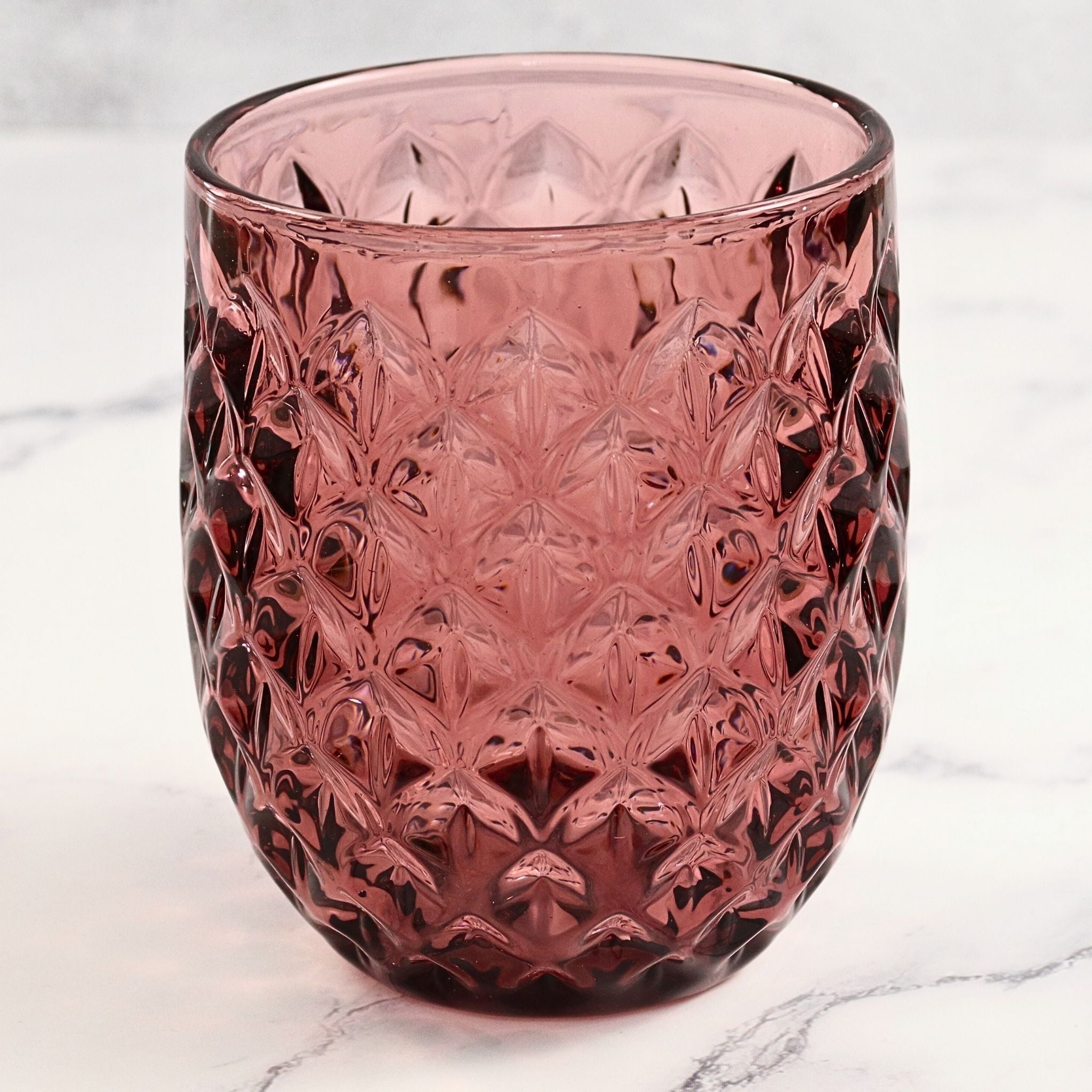 purple glass tumbler with textured design on a marble surface