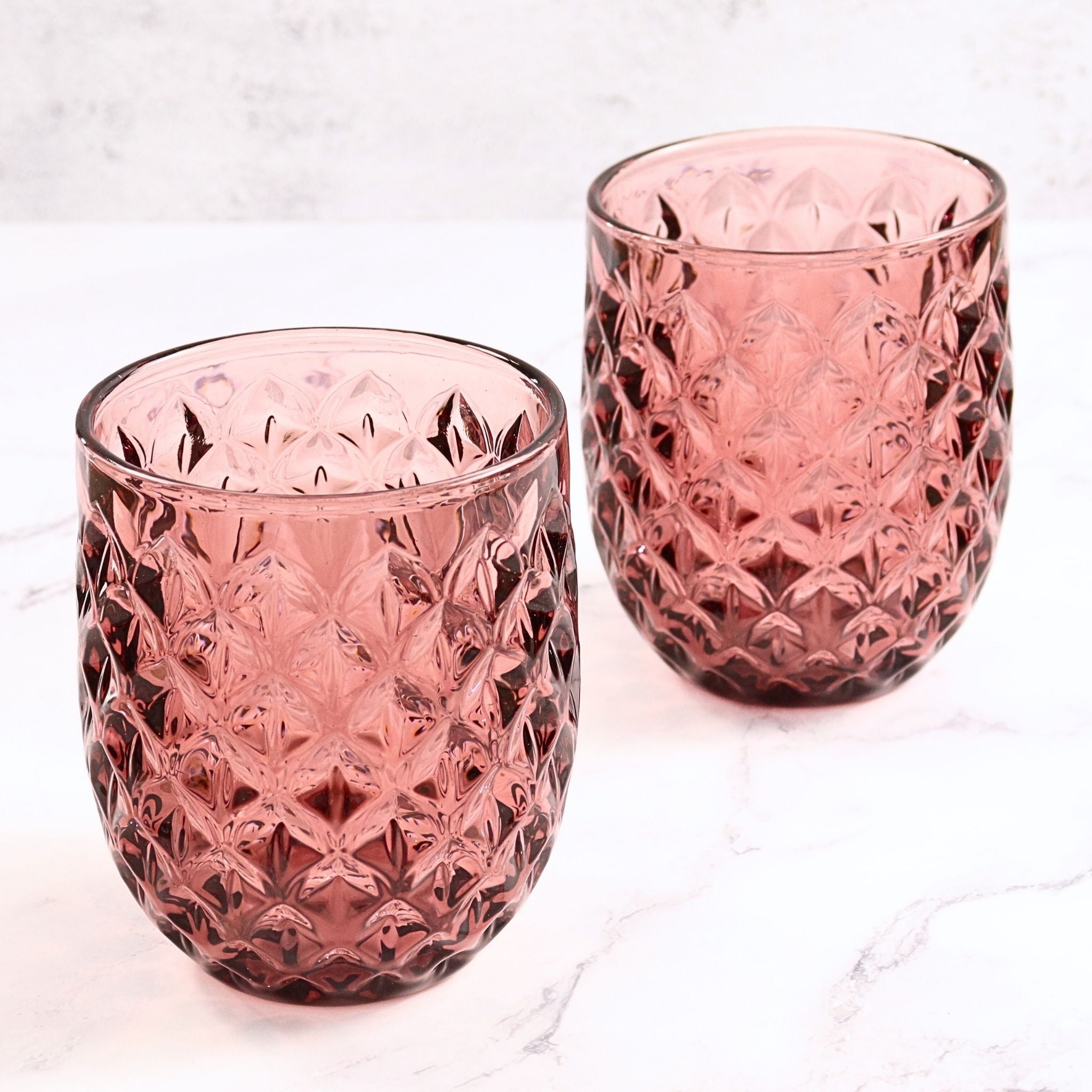 Two purple textured glass tumblers on a white background