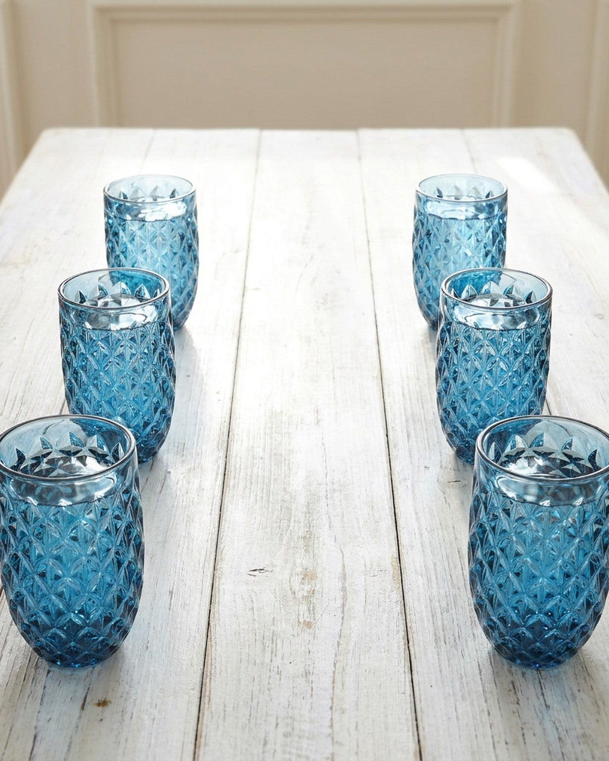 Set of blue textured glass tumblers on a wooden surface
