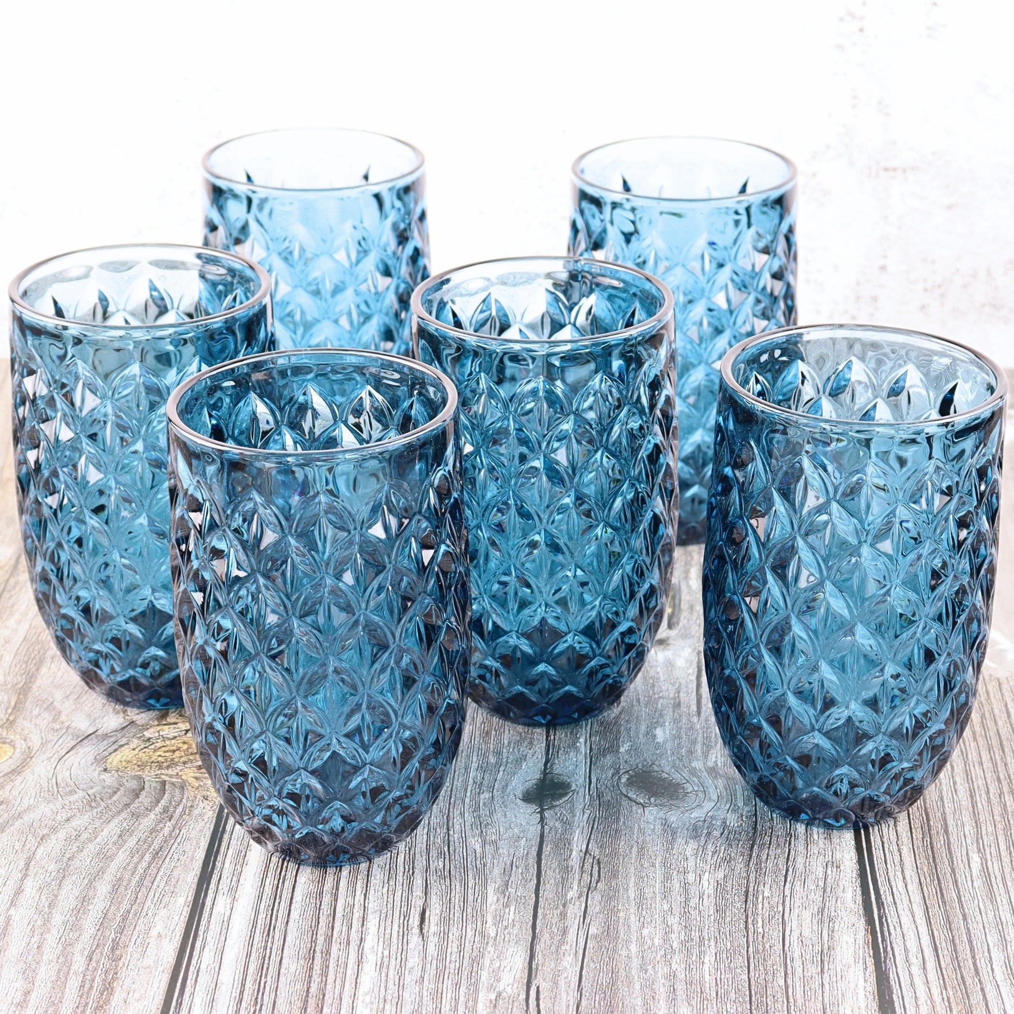 Set of six blue textured glass tumblers on a wooden surface