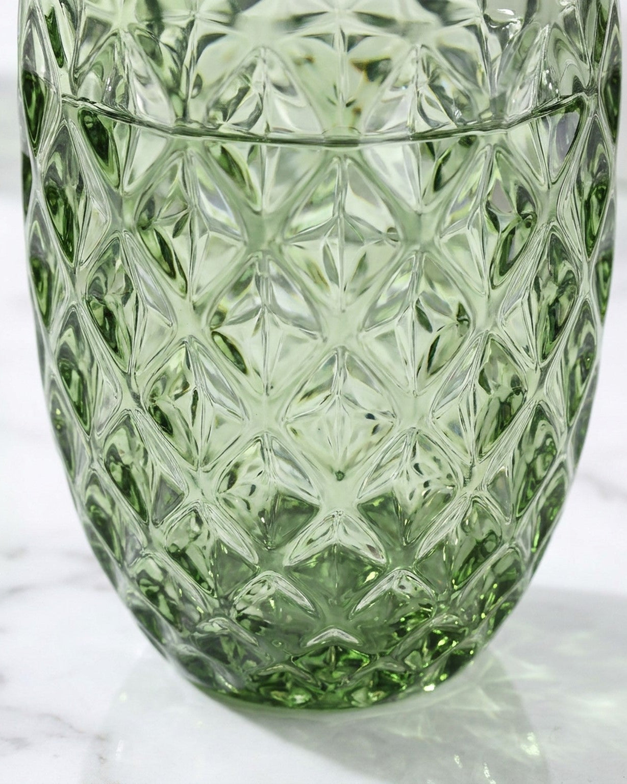 Green glass tumbler with diamond pattern on a light background