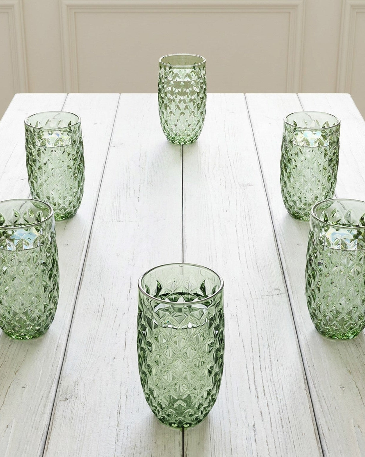 Set of green textured glass tumblers on a wooden surface