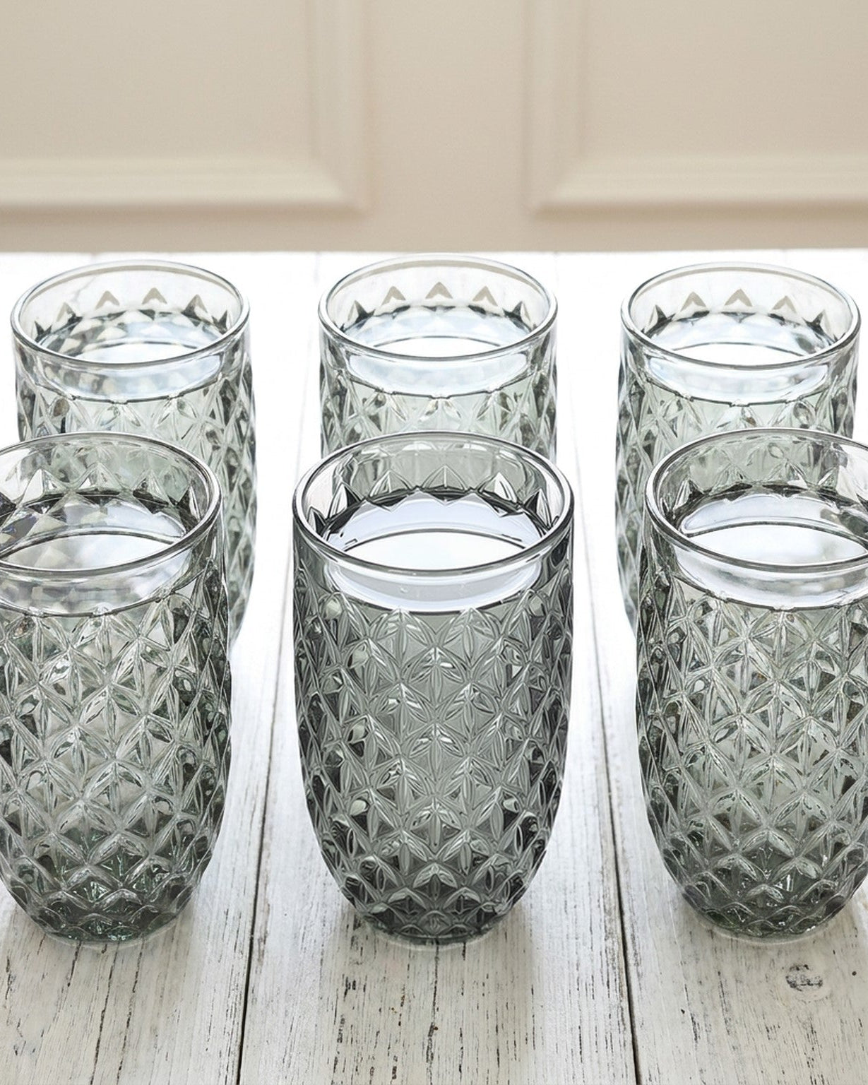 Set of six textured glass tumblers on a wooden surface