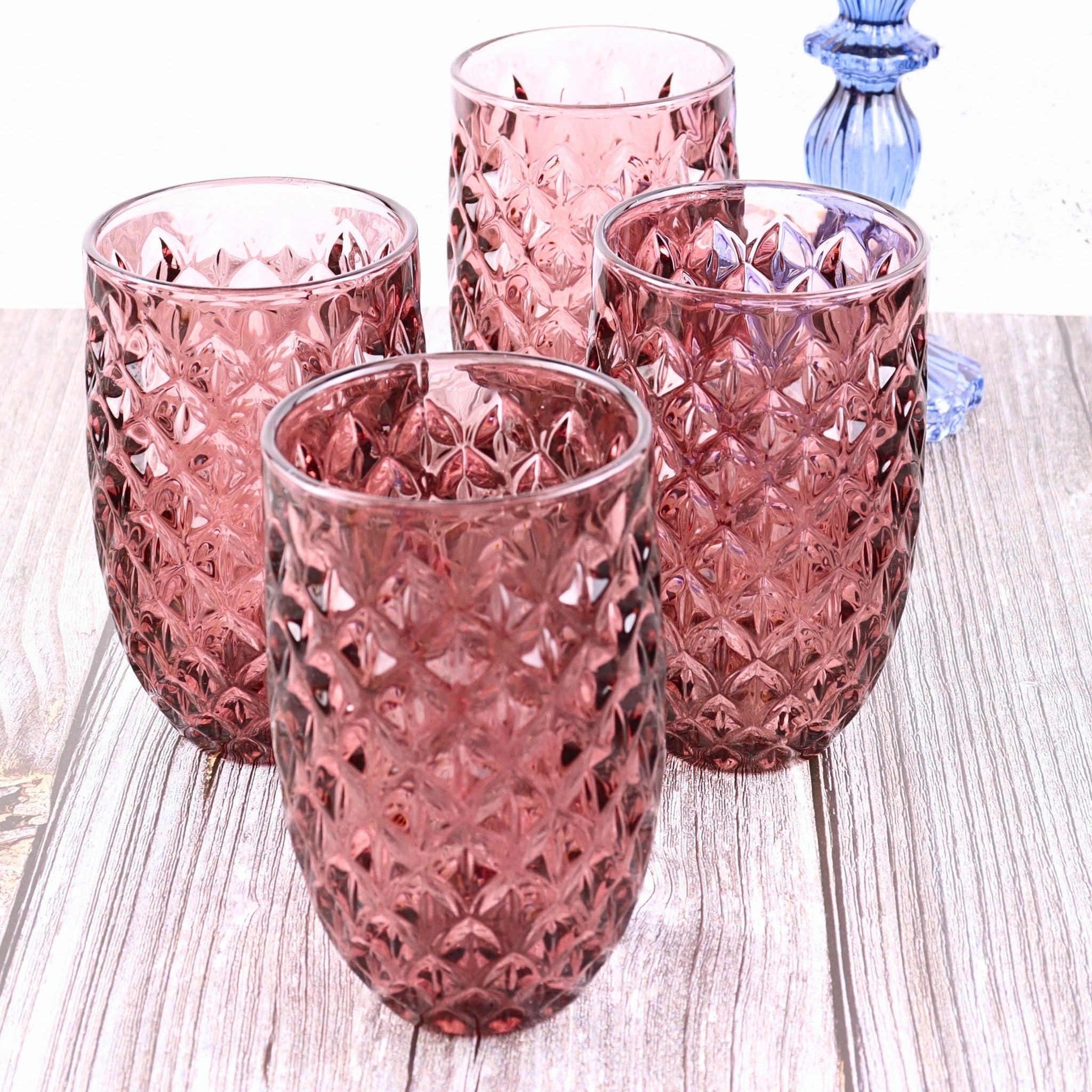 Set of four pink textured glass tumblers on a wooden surface
