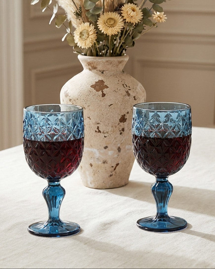 Set of six blue glass goblets with textured design on a light gray background