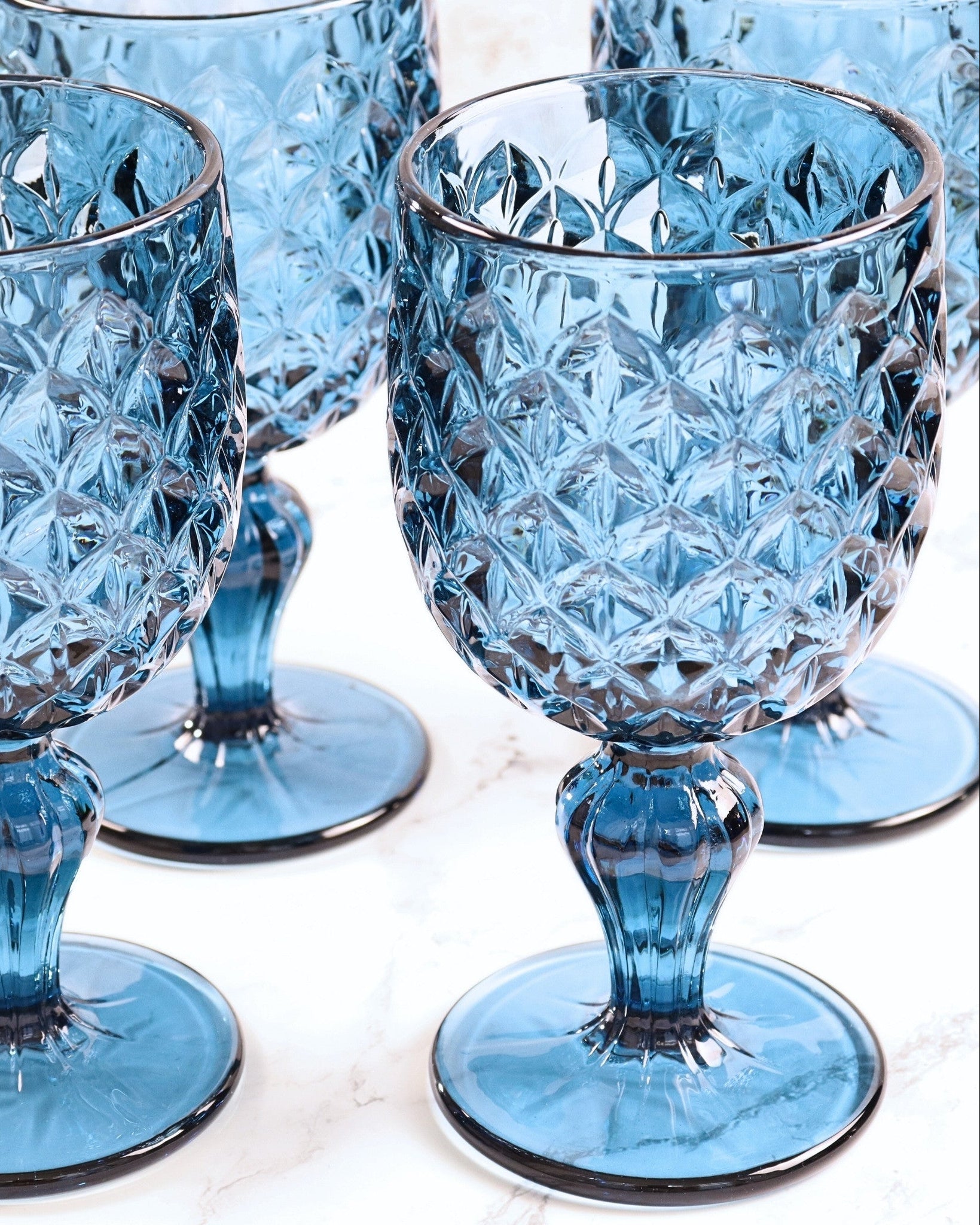 Set of 4 blue crystal goblets on a light background