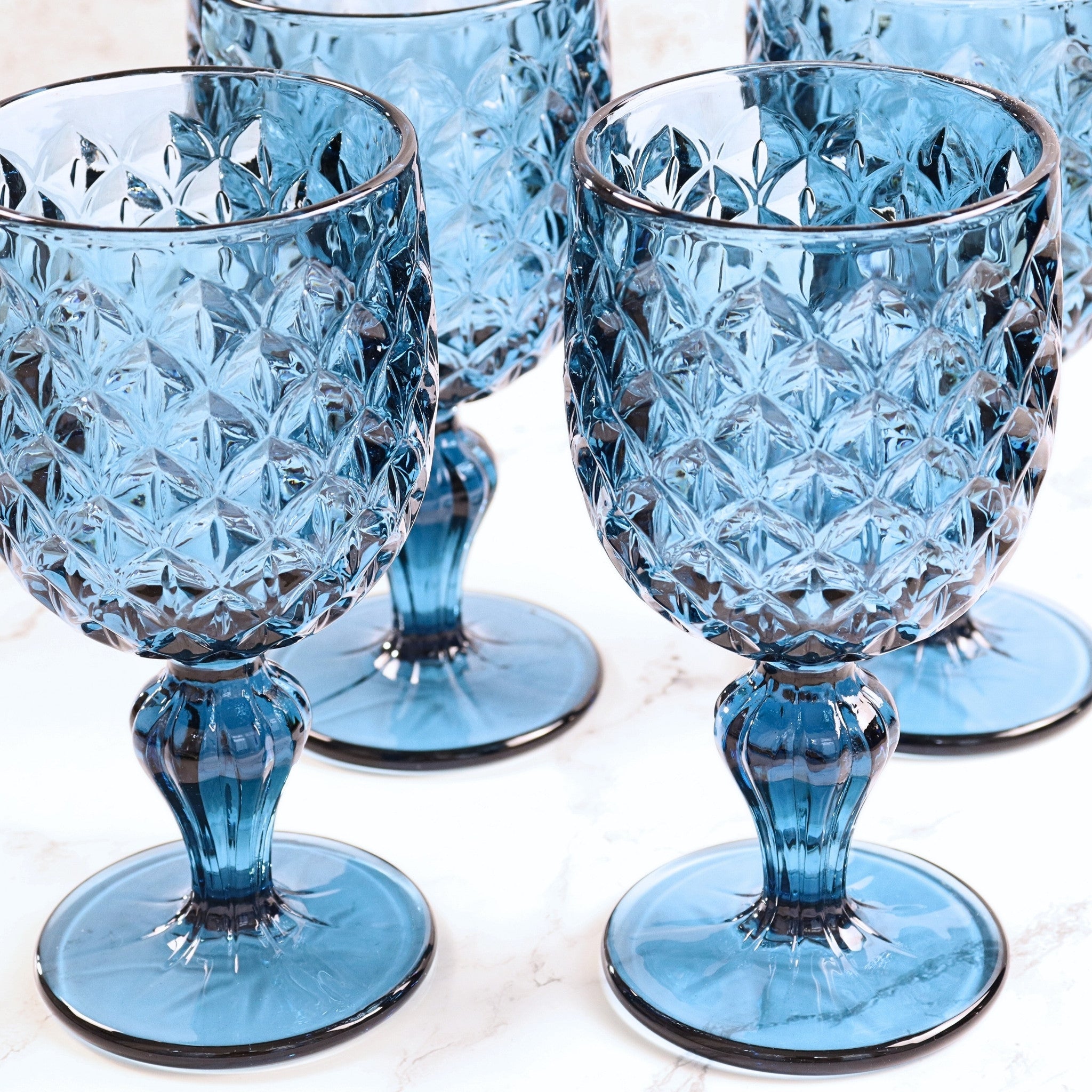 Set of 4 blue crystal goblets on a light background