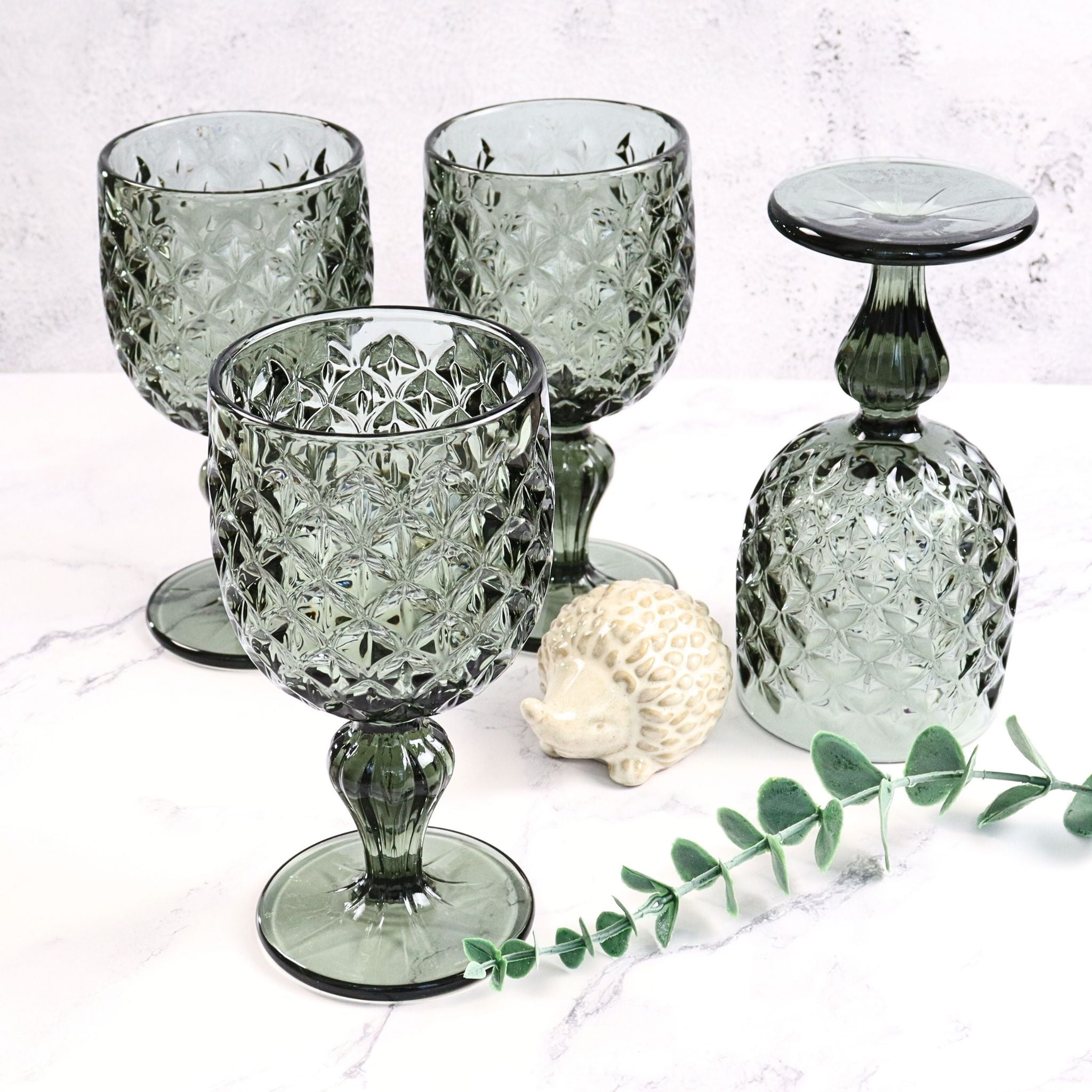 Set of decorative glass goblets on a white surface with a light background