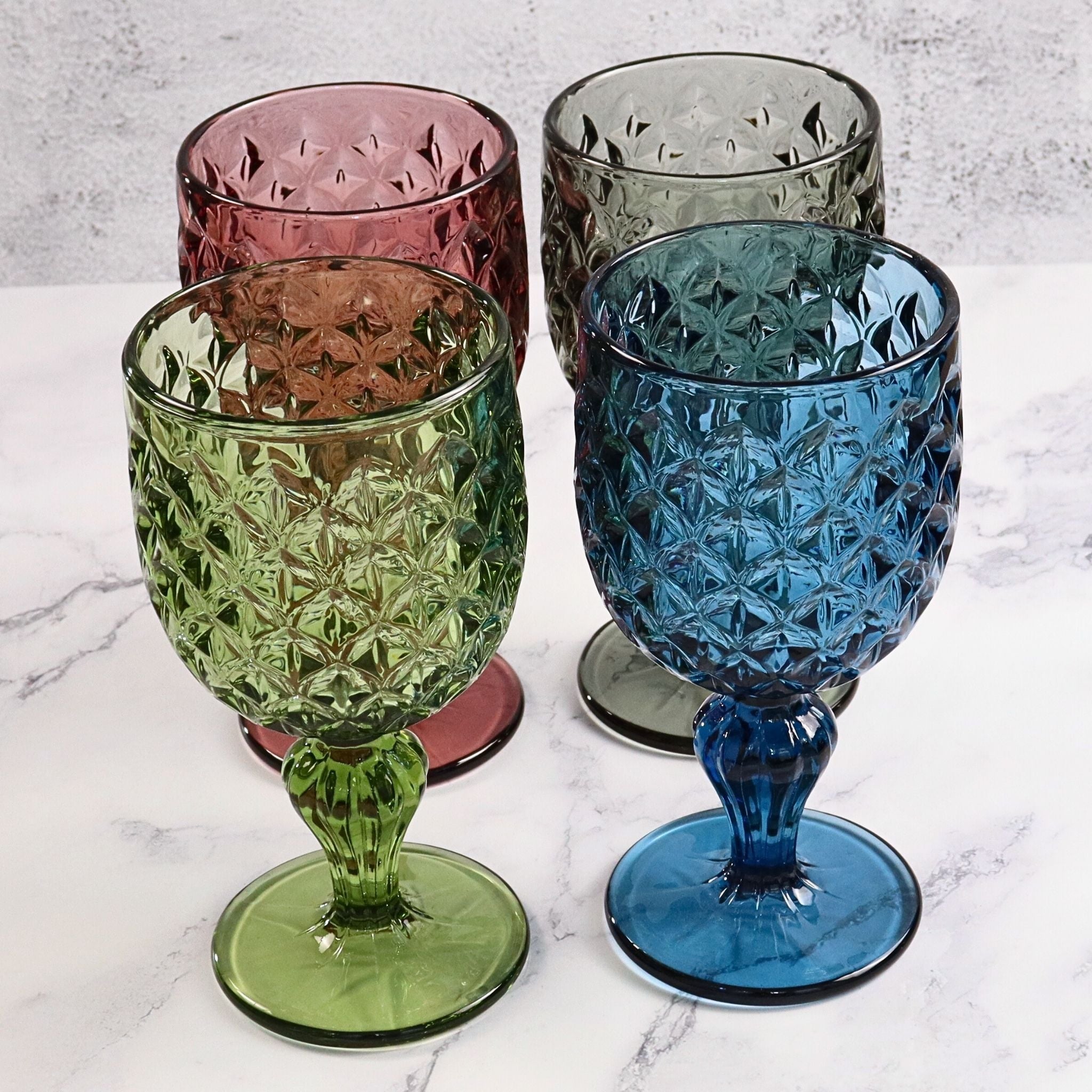 Four colorful glass goblets on a marble surface