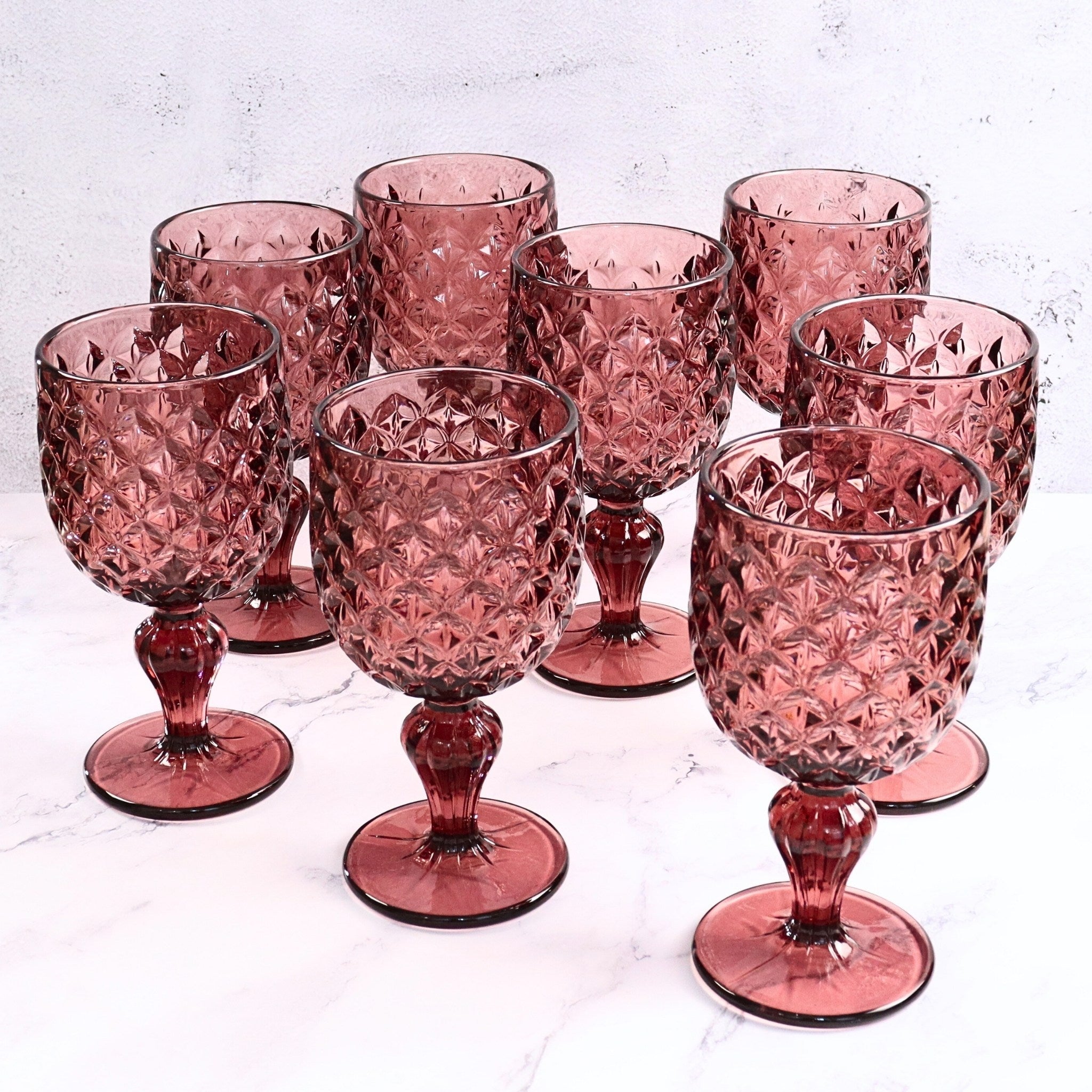 Set of purple glass goblets with textured design on a light gray background