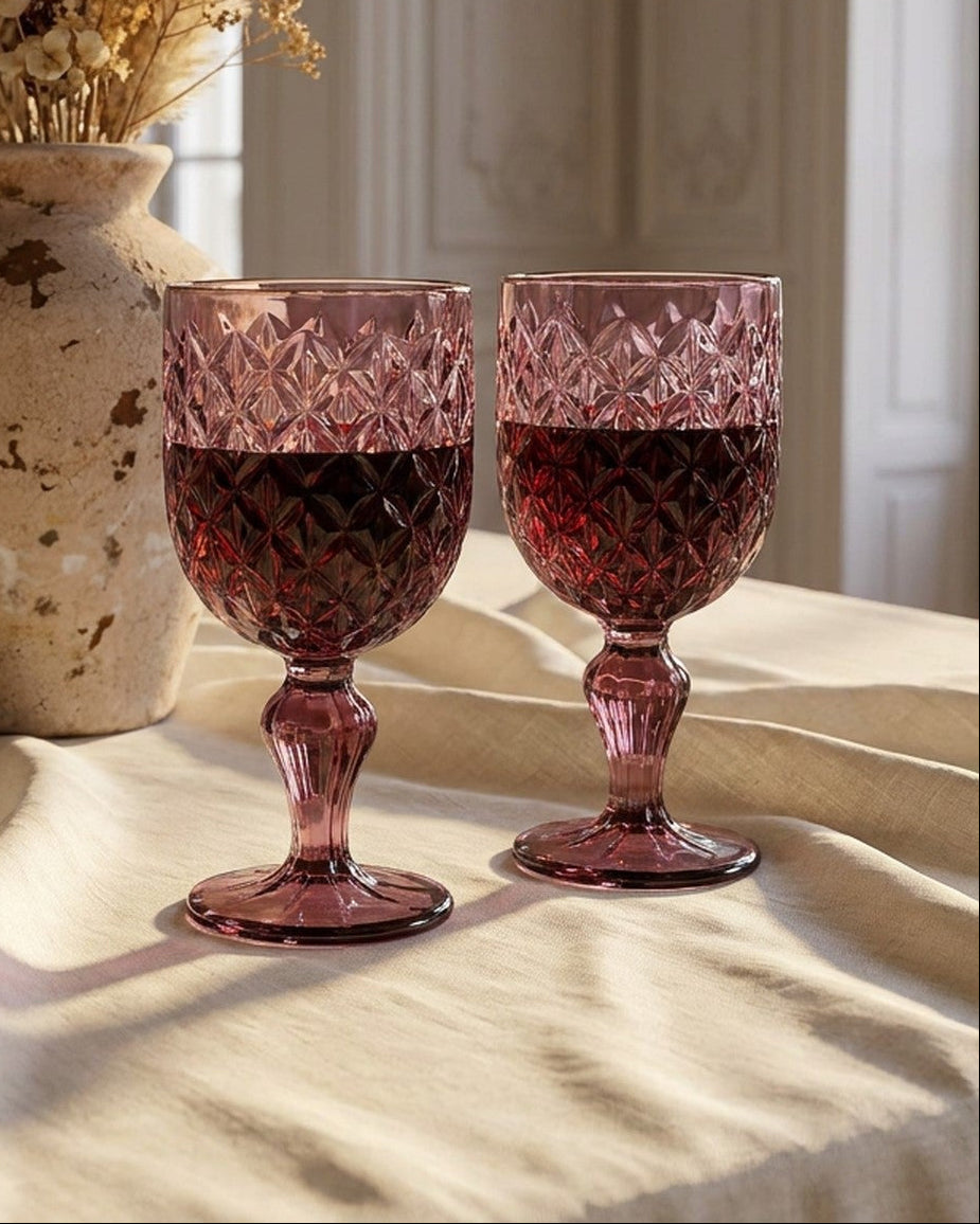 Two purple crystal goblets on a light gray marble surface