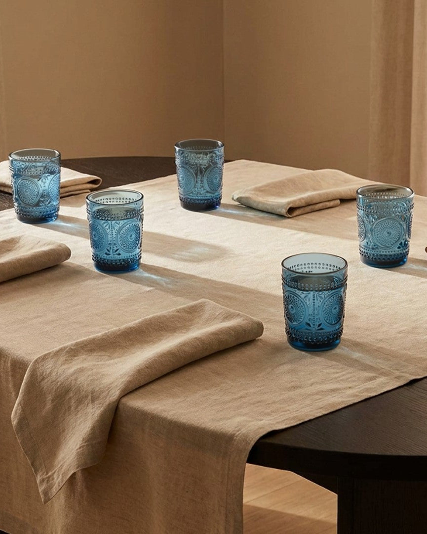 Set of blue glass tumblers with embossed patterns on a white surface.