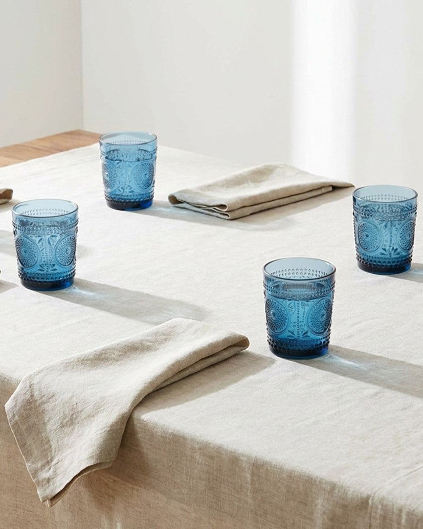 Set of six blue glass tumblers with textured design on a white surface.