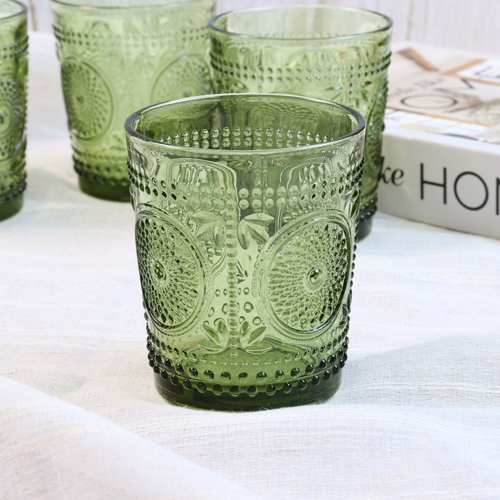 Green glass tumbler with decorative pattern on a white surface