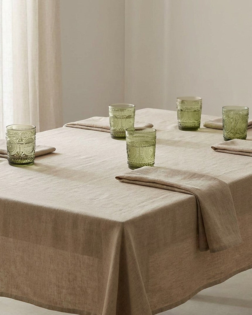 Set of six green patterned glass tumblers on a white surface