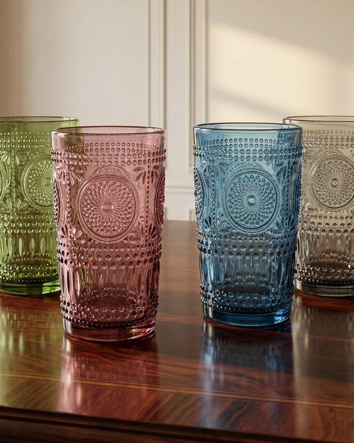 Four colorful glass tumblers on a wooden table with a classical interior background