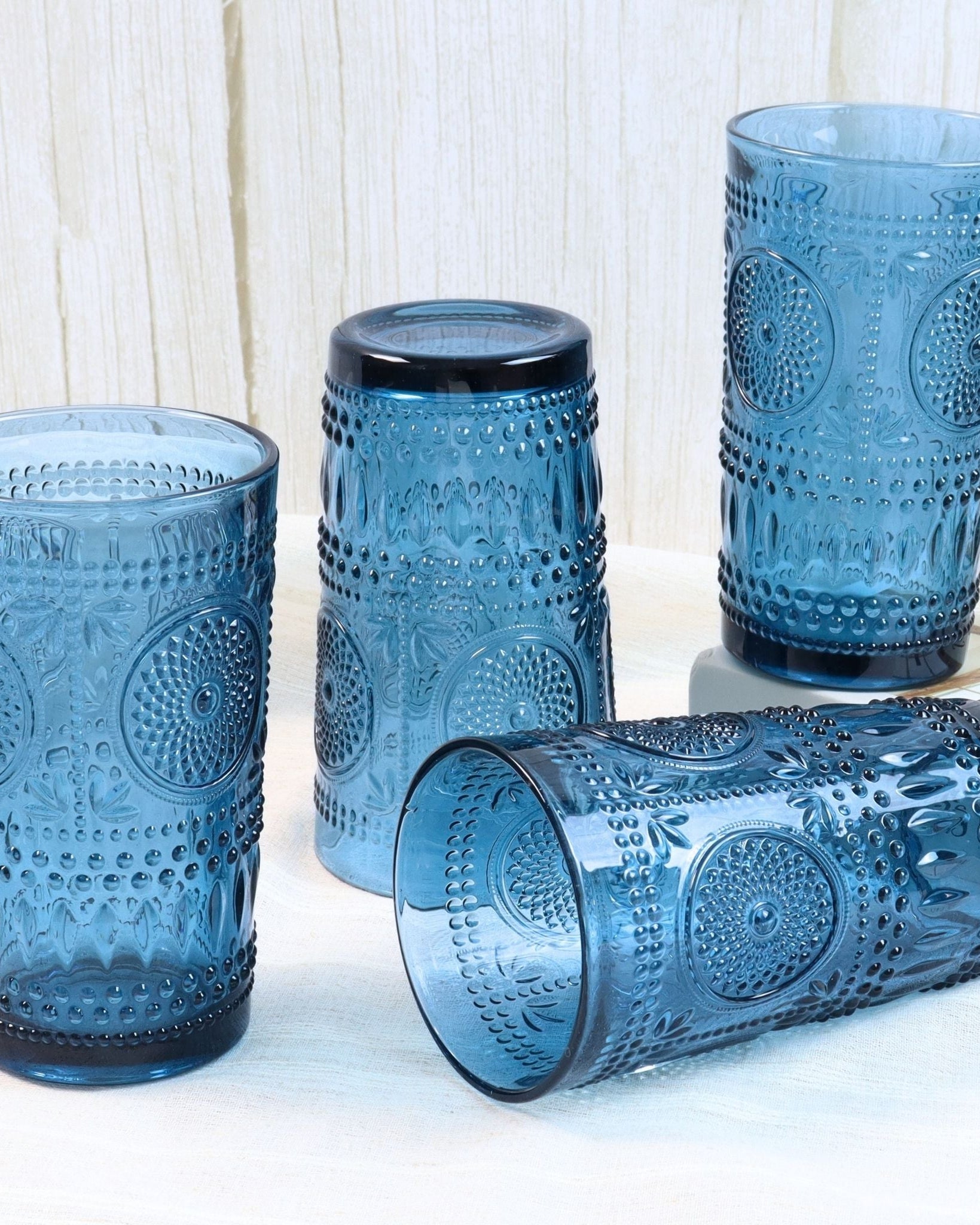 Set of blue textured glass tumblers on a white surface with a light wooden background