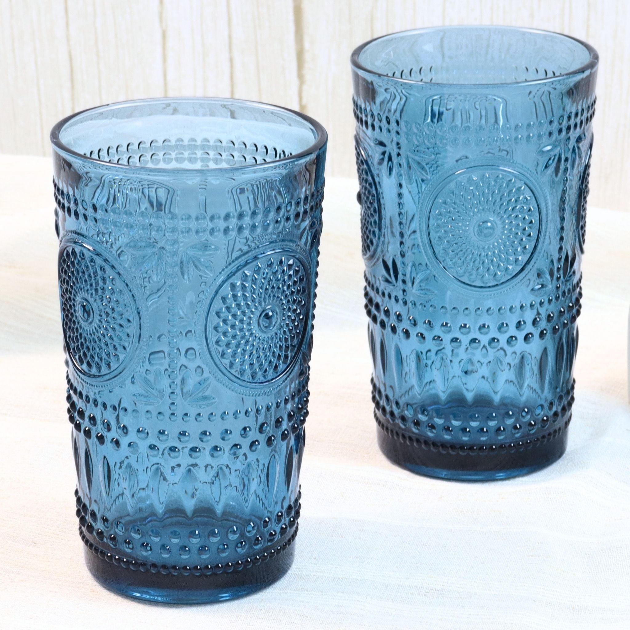 Two blue textured glass tumblers on a white surface with a light background