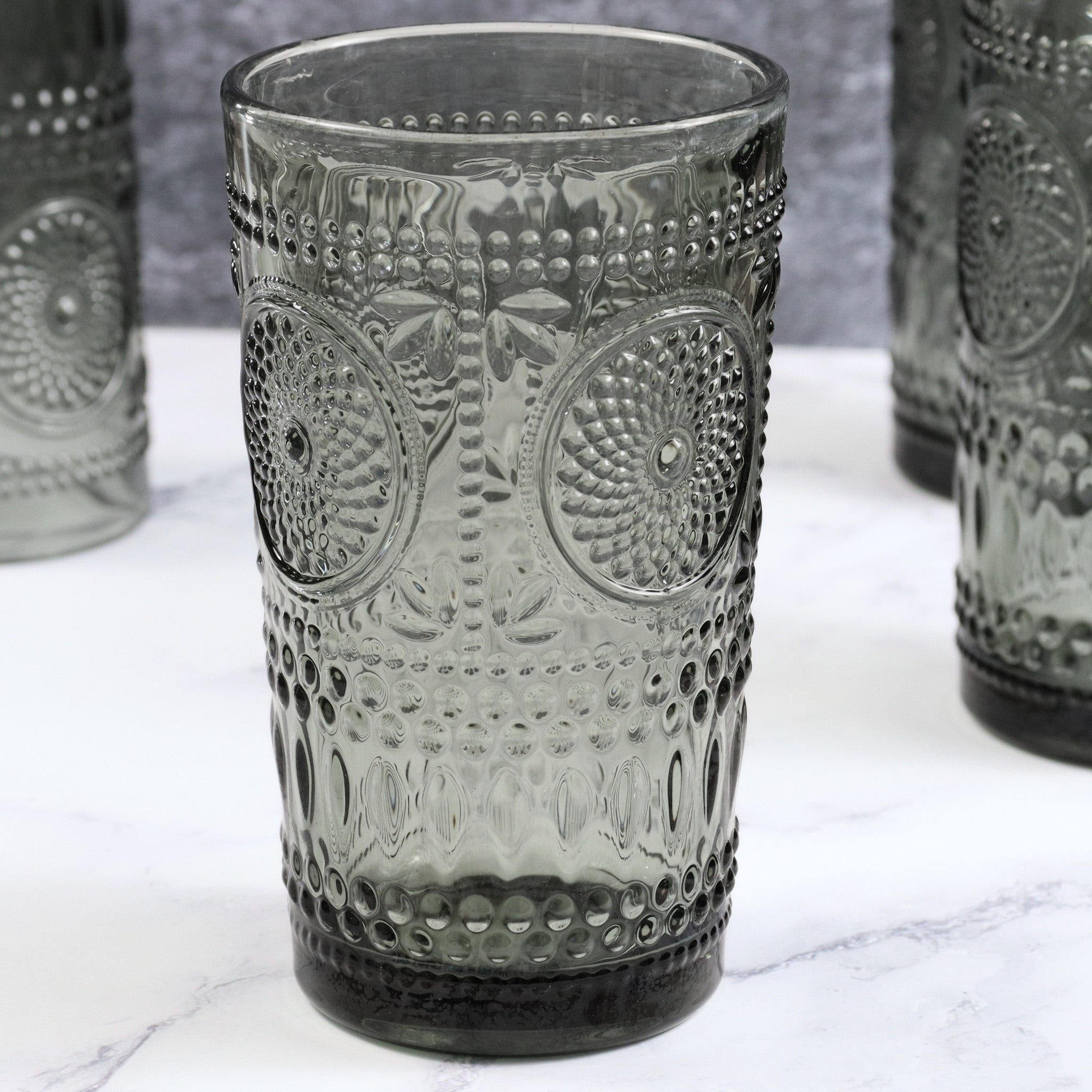 Decorative glass tumbler with embossed patterns on a marble surface