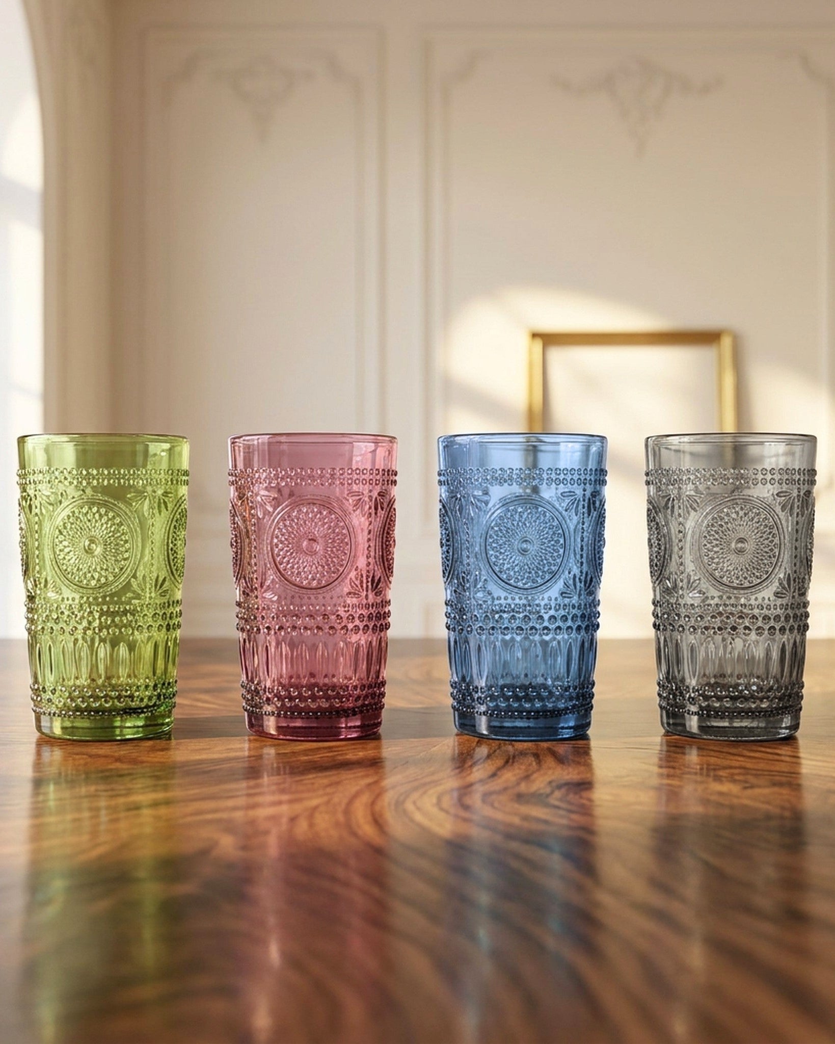 Four colorful glass tumblers on a wooden table with a neutral background