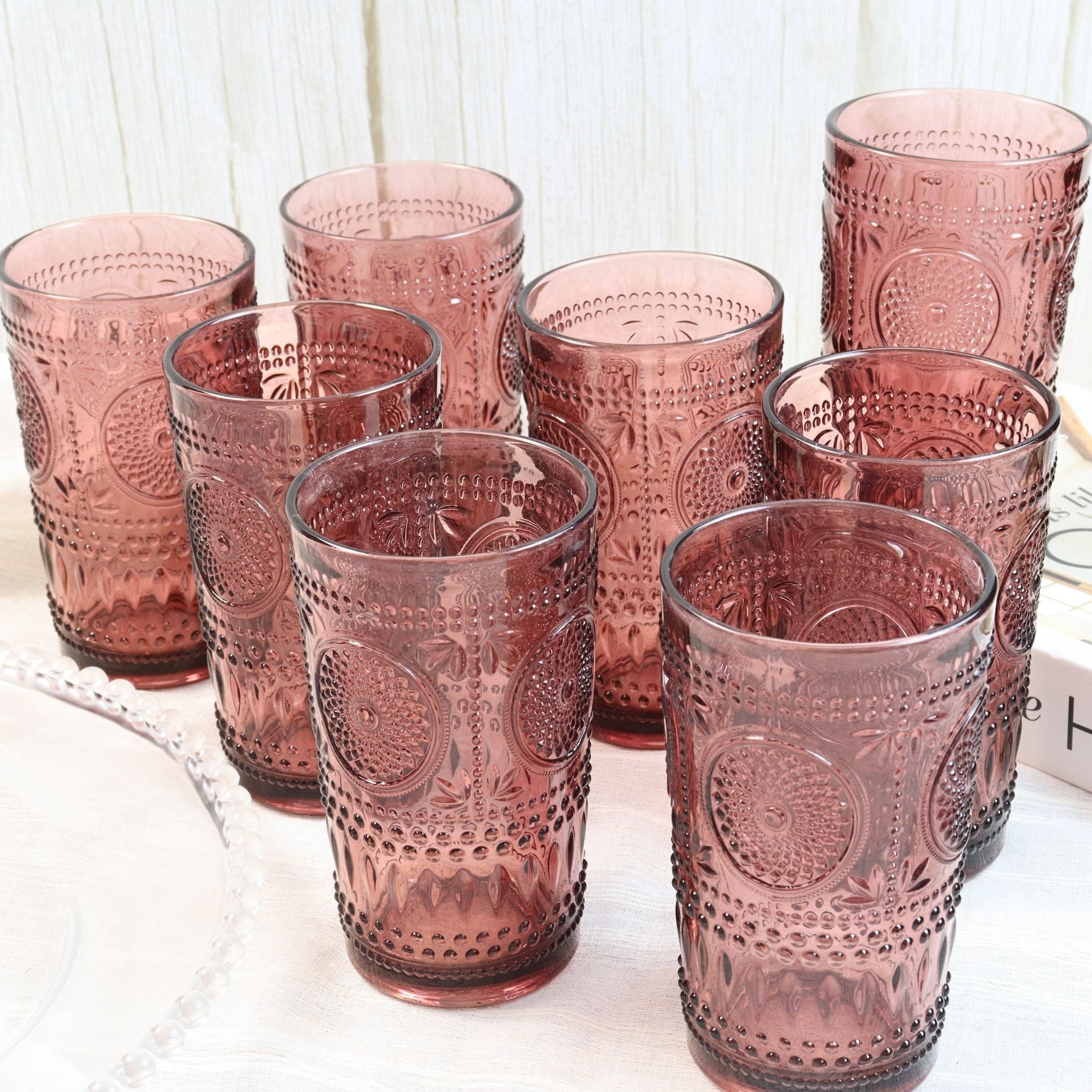 Set of purple glass tumblers with embossed designs on a white surface.