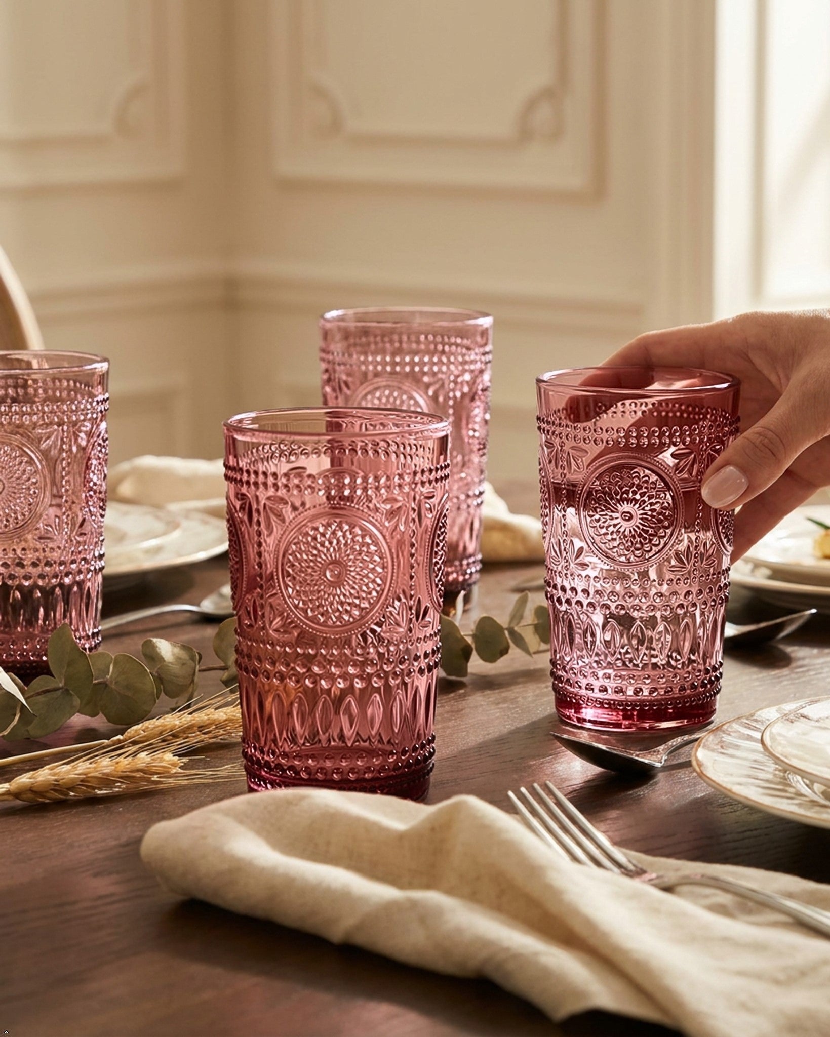 Set of purple glass tumblers with embossed designs on a white surface.