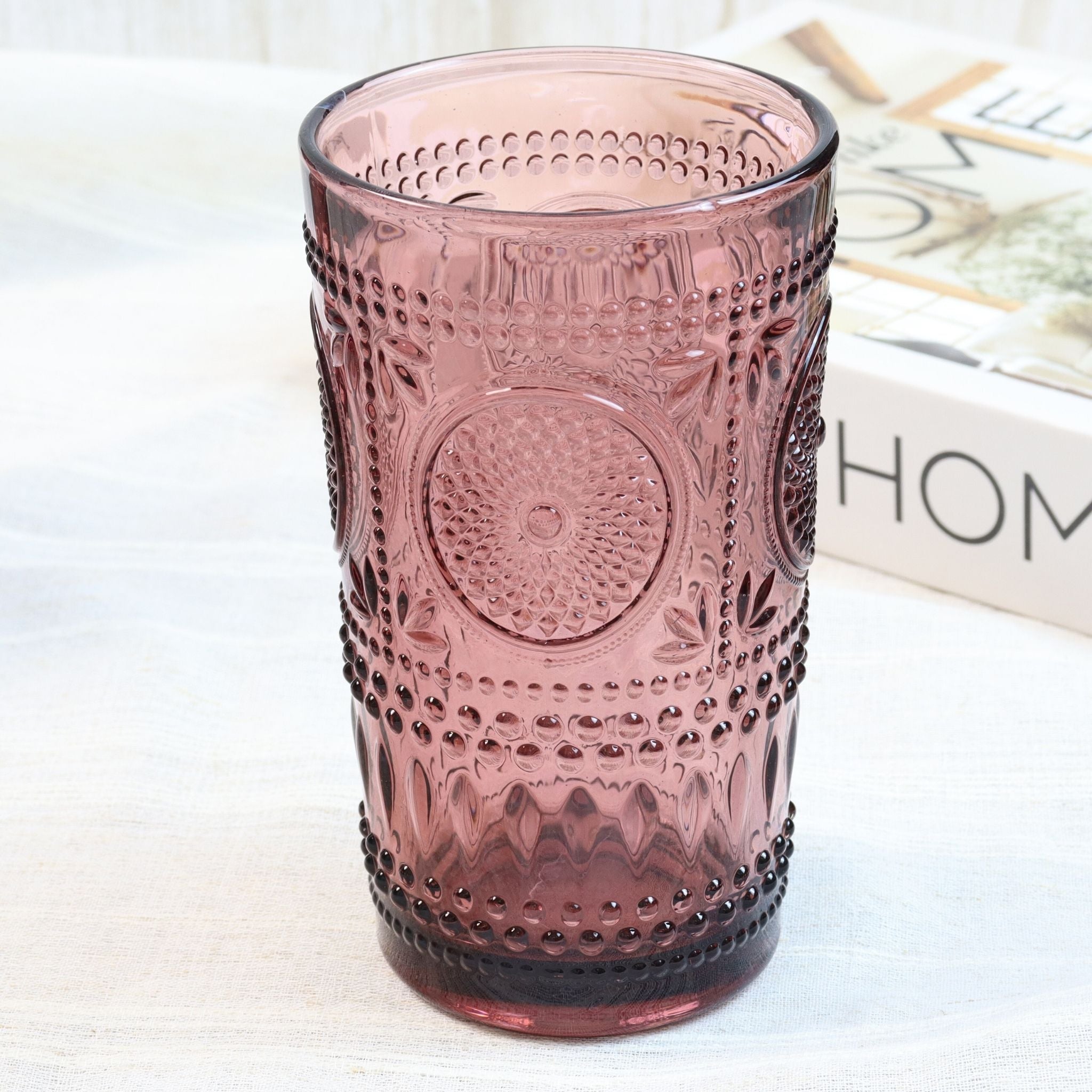 purple textured glass tumbler on a white surface with a blurred background