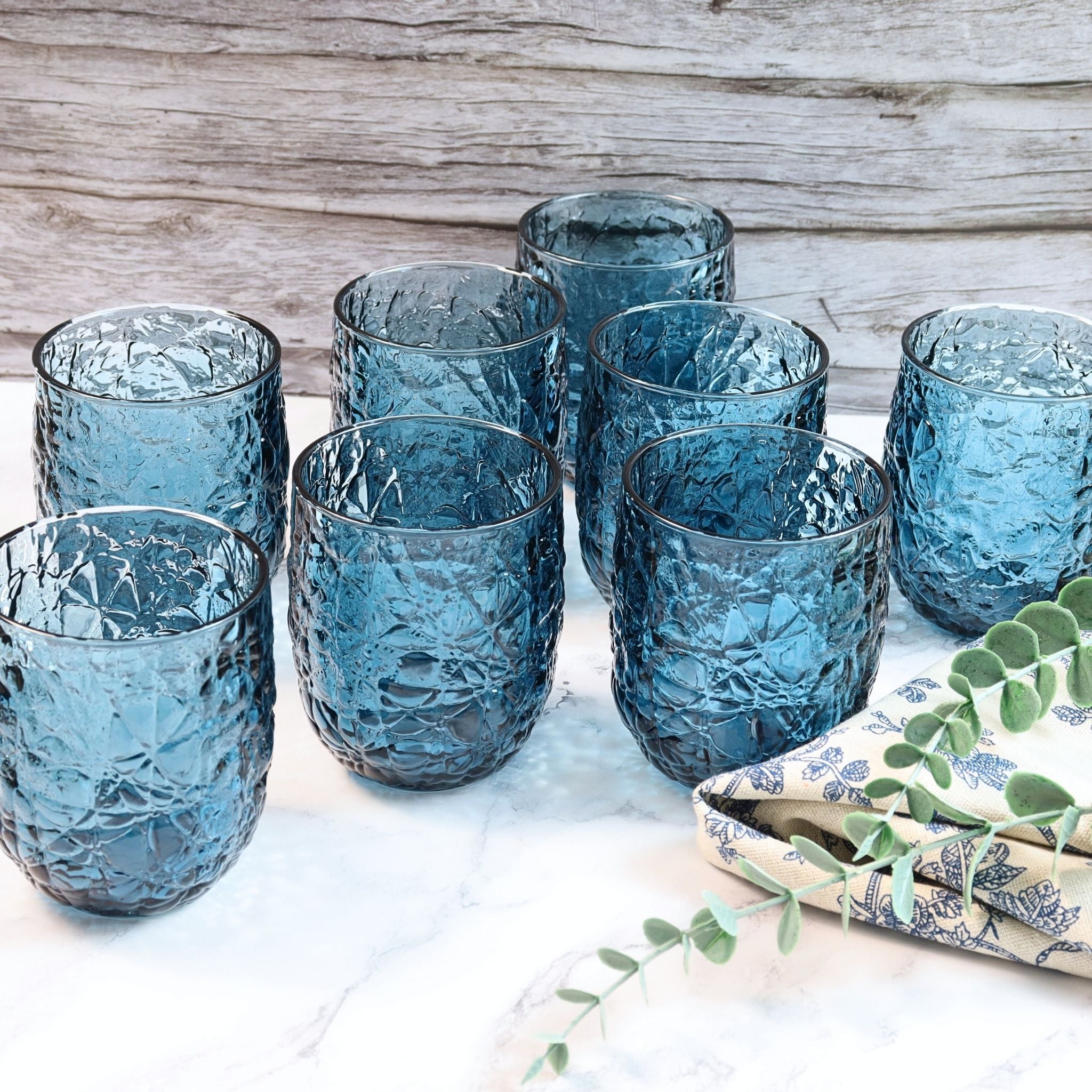 Set of blue textured glasses on a marble surface with a wooden background