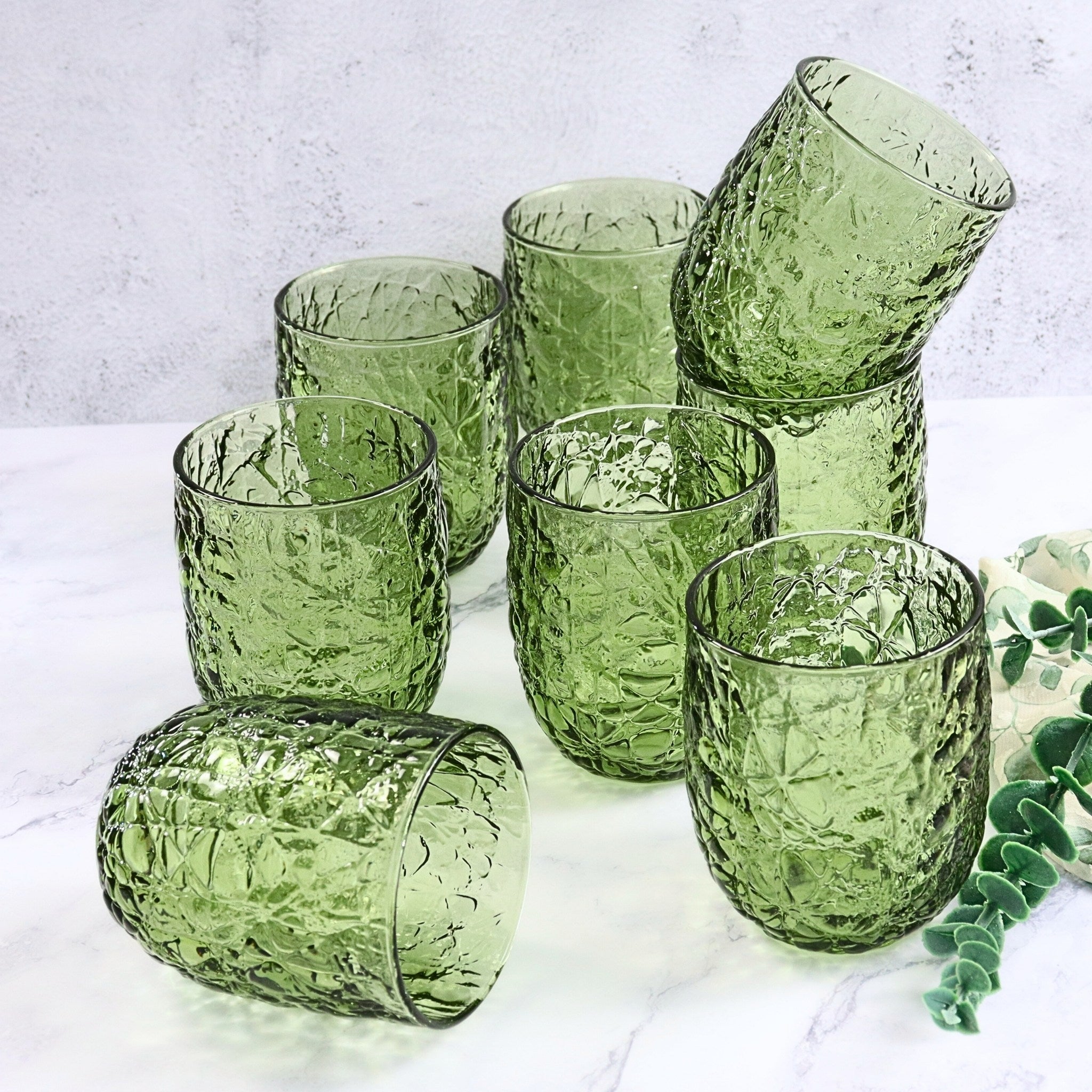 Set of green textured glass tumblers on a light background