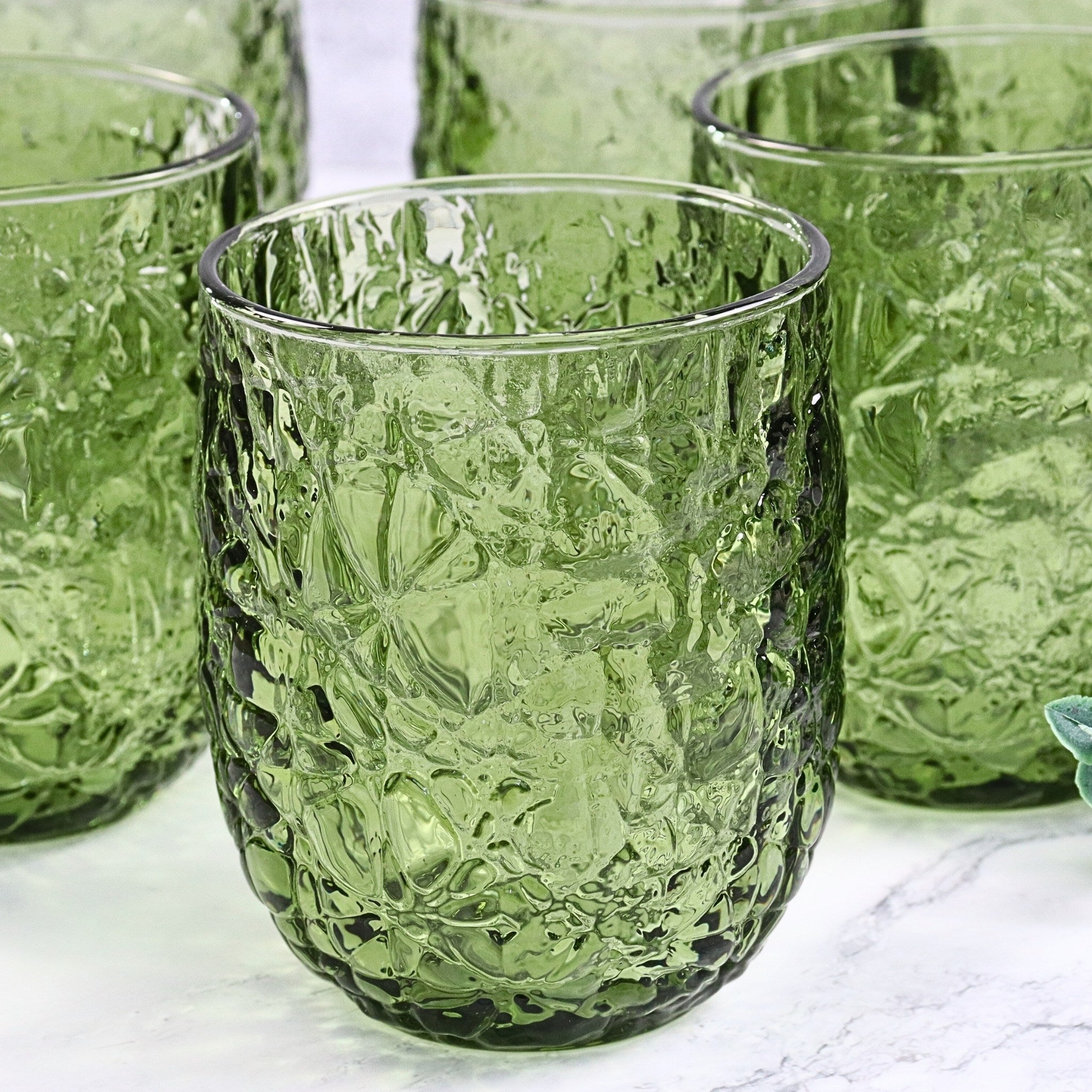 Green textured glass tumblers on a white surface