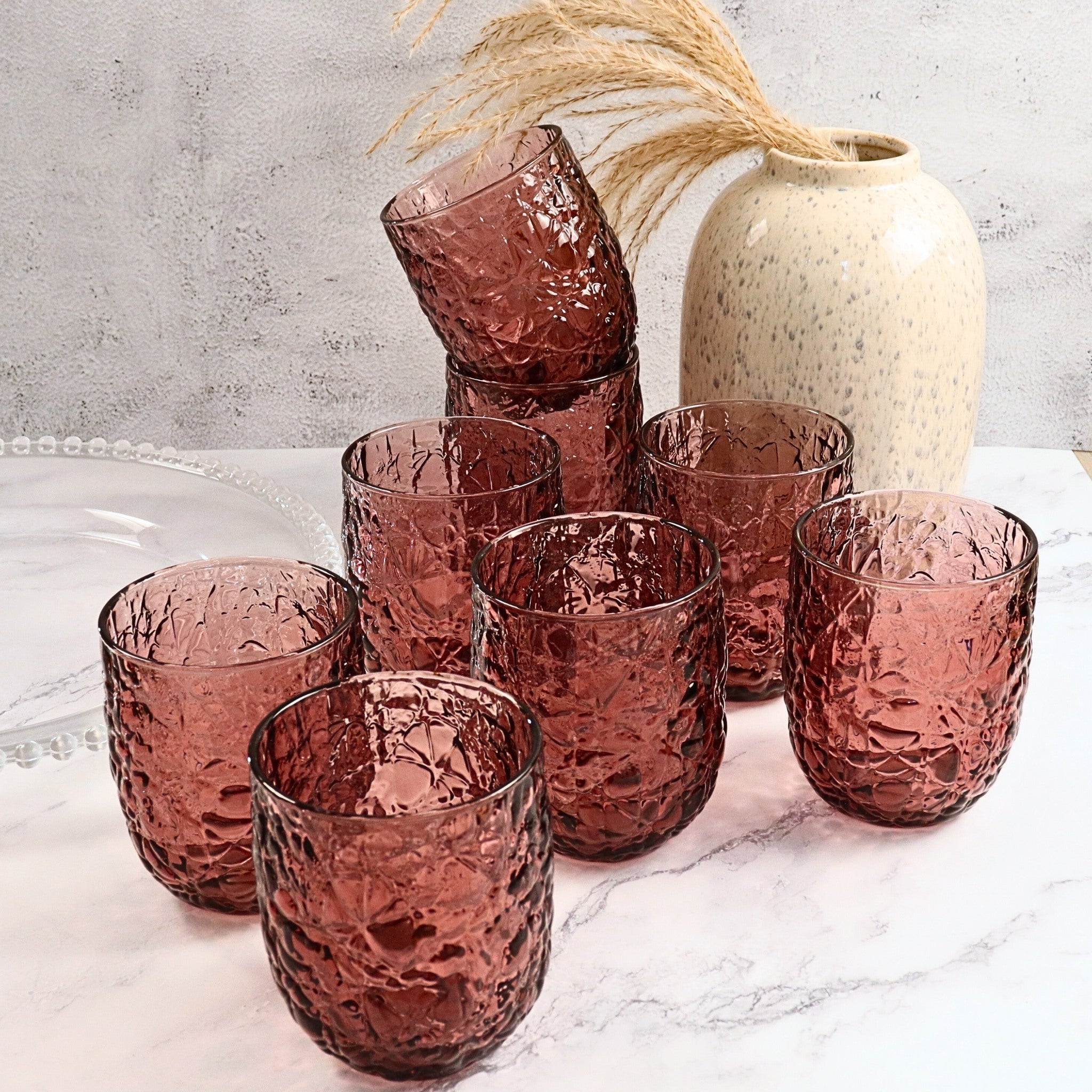 Set of purple textured glasses on a marble surface with a neutral background