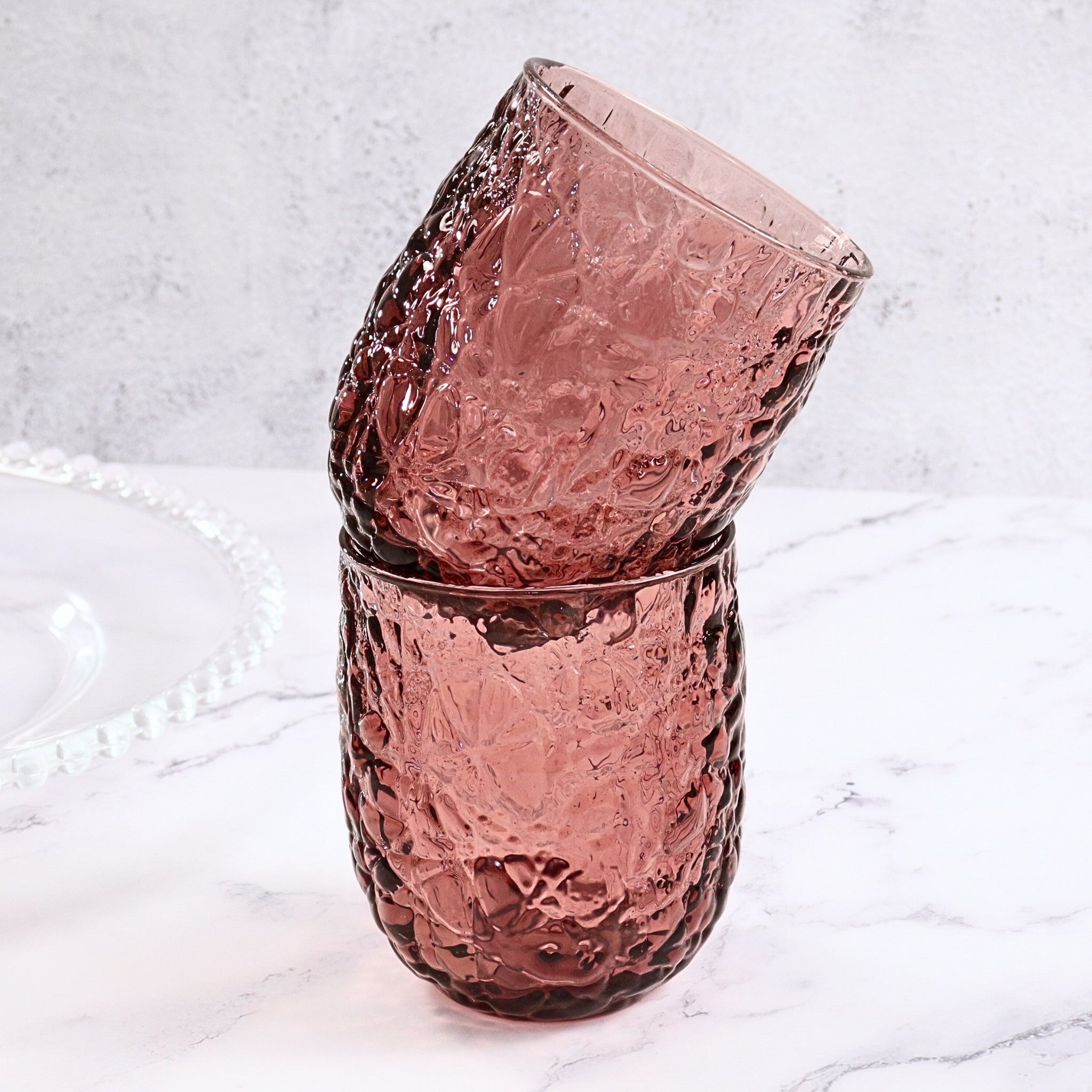 Stack of purple textured glass tumblers on a marble surface