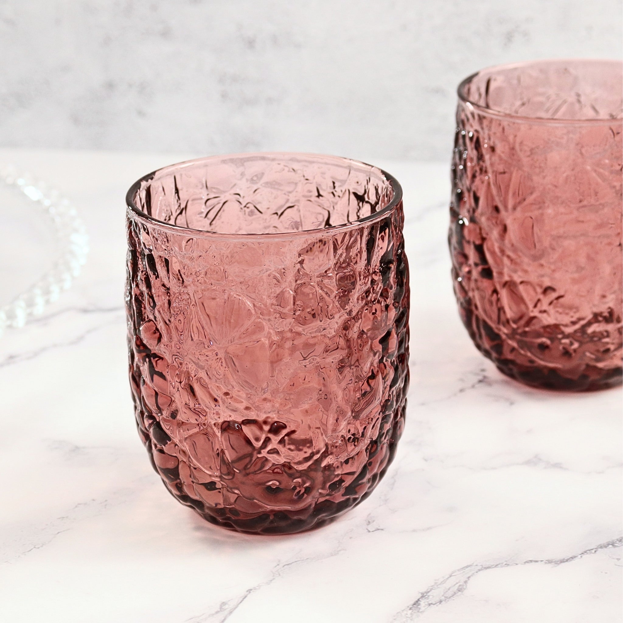 Two purple textured glass tumblers on a marble surface