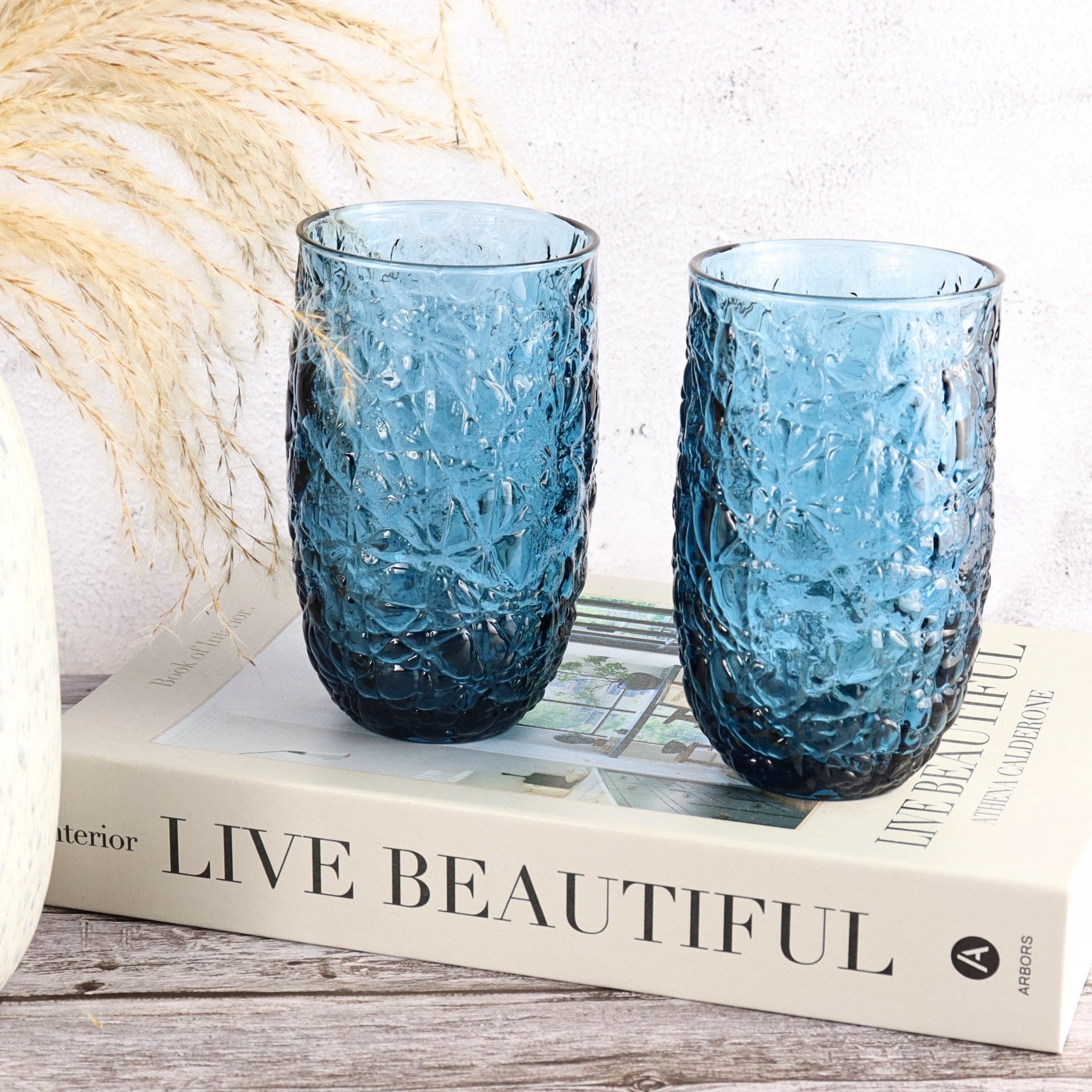 Two blue textured glasses on a book titled 'Live Beautiful'.