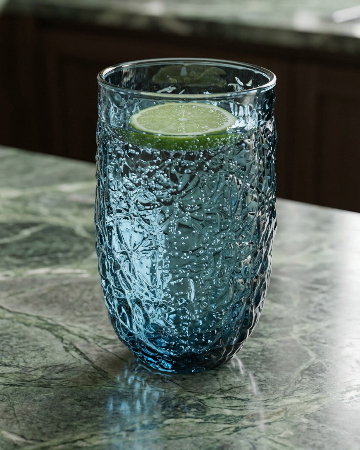 Two textured blue glass tumblers on a wooden surface