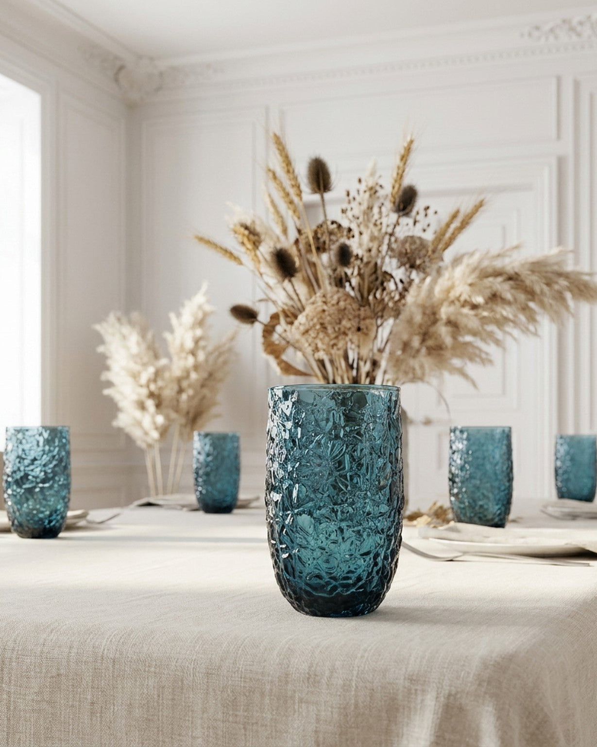 Two textured blue glass tumblers on a wooden surface