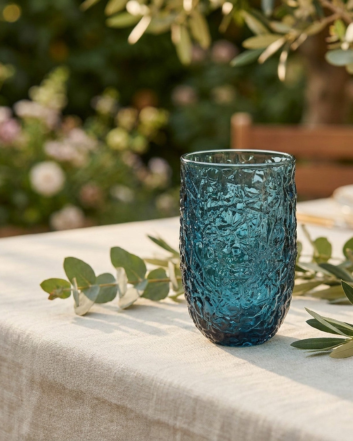 Two textured blue glass tumblers on a wooden surface