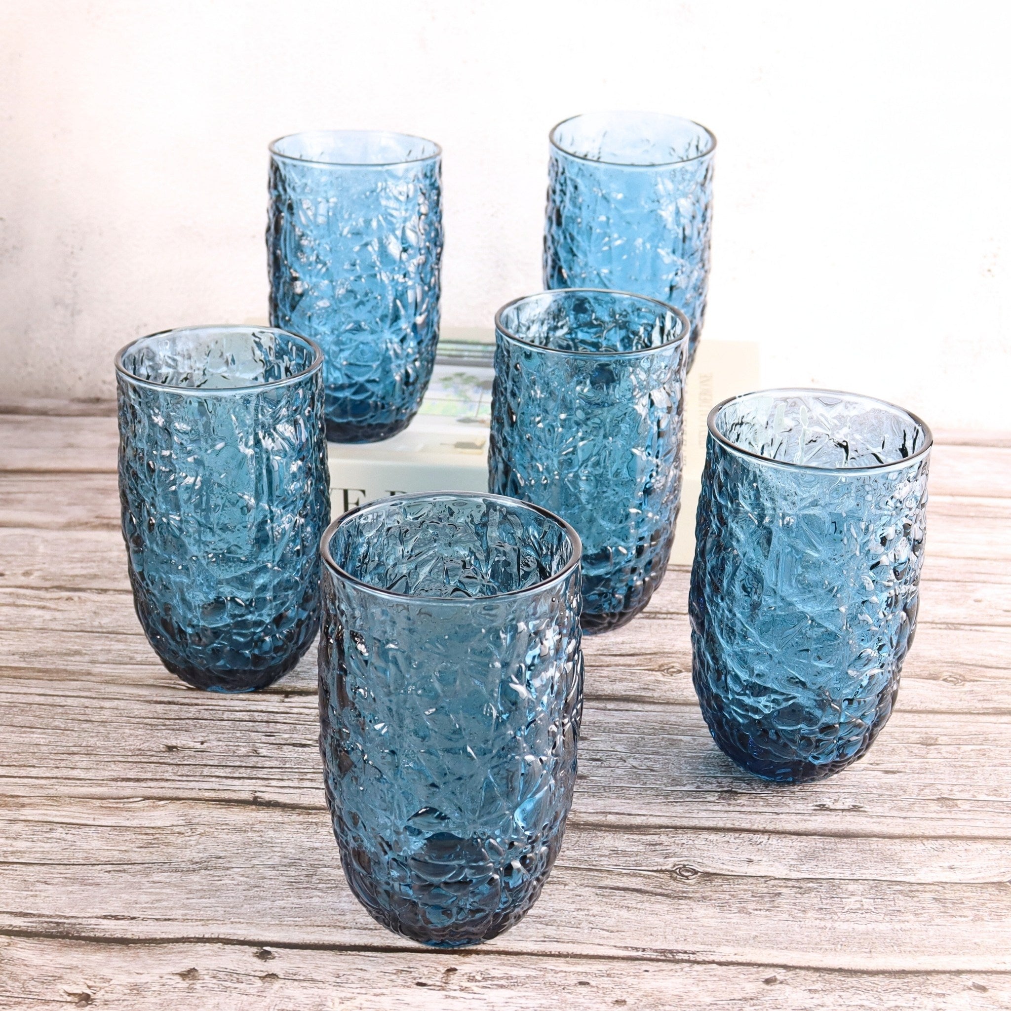 Set of six blue textured glass tumblers on a wooden surface