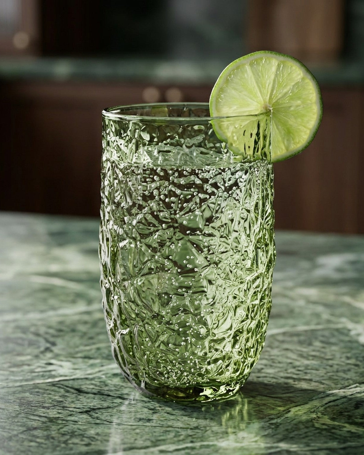 Green textured glass tumblers on a wooden surface with books in the background