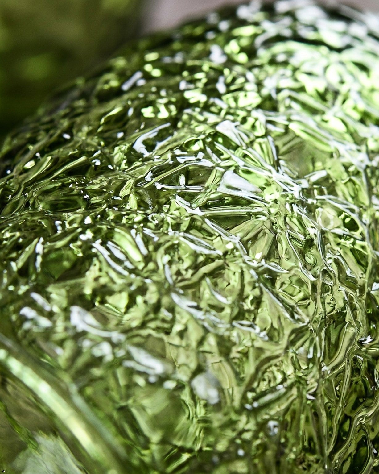 Green textured glass tumblers on a wooden surface with books in the background
