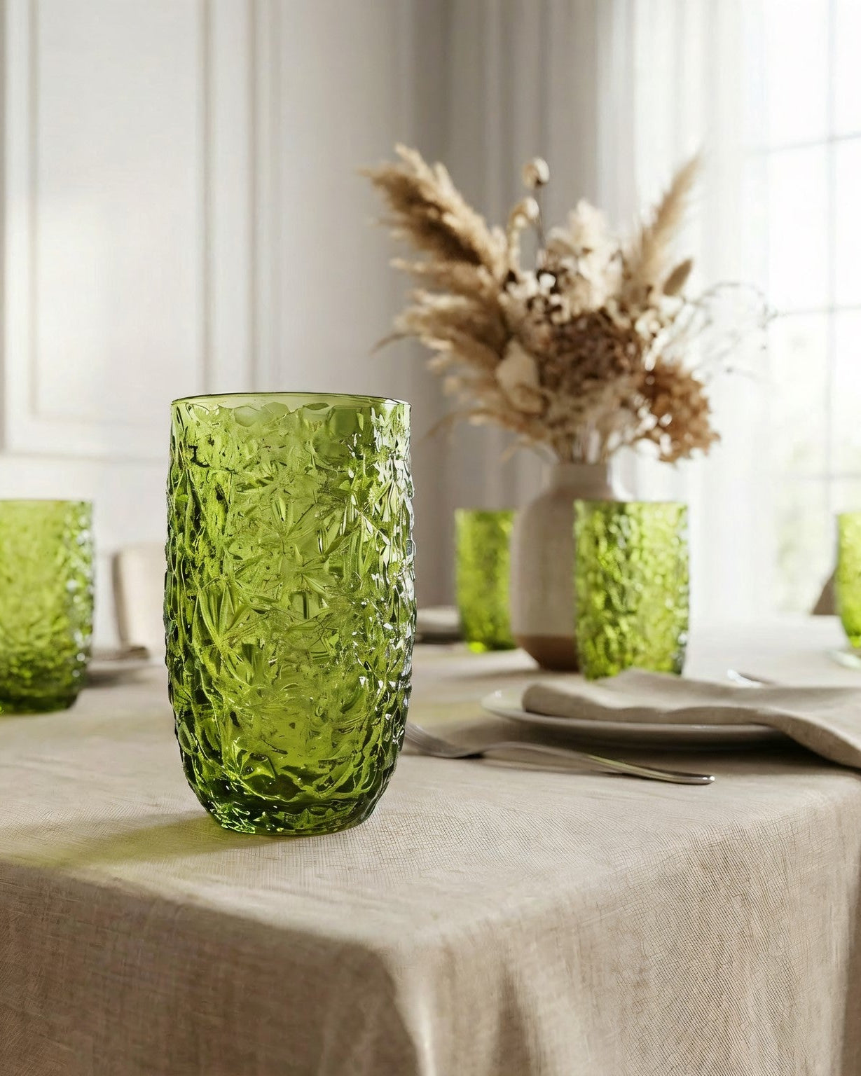 Green textured glass tumblers on a wooden surface with books in the background.