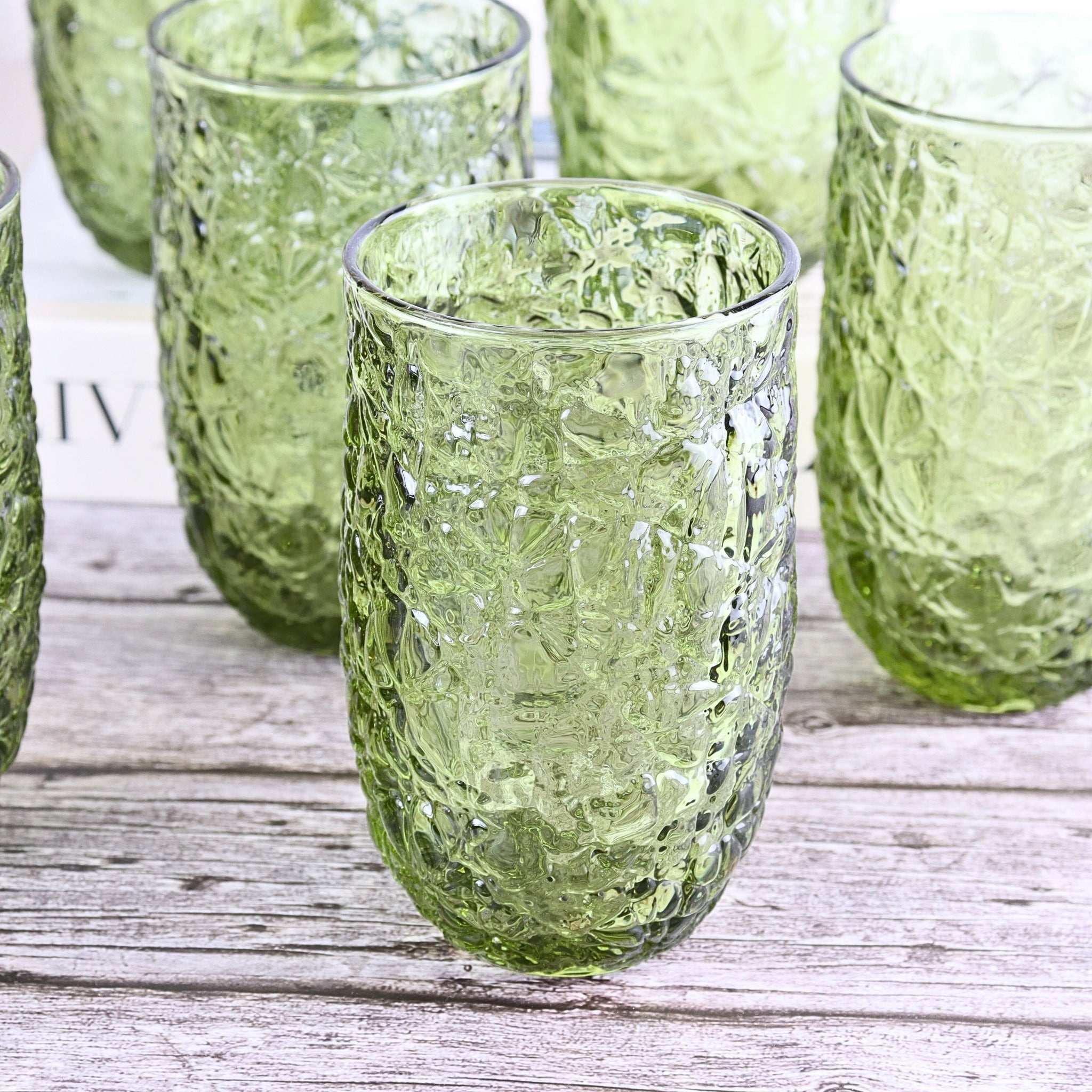 Set of green textured glass tumblers on a wooden surface