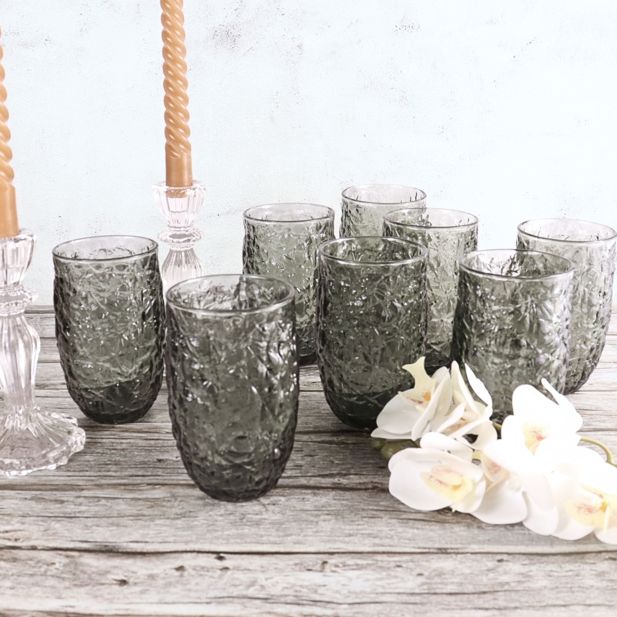 Set of 8 textured glass tumblers on a wooden surface with white flowers.