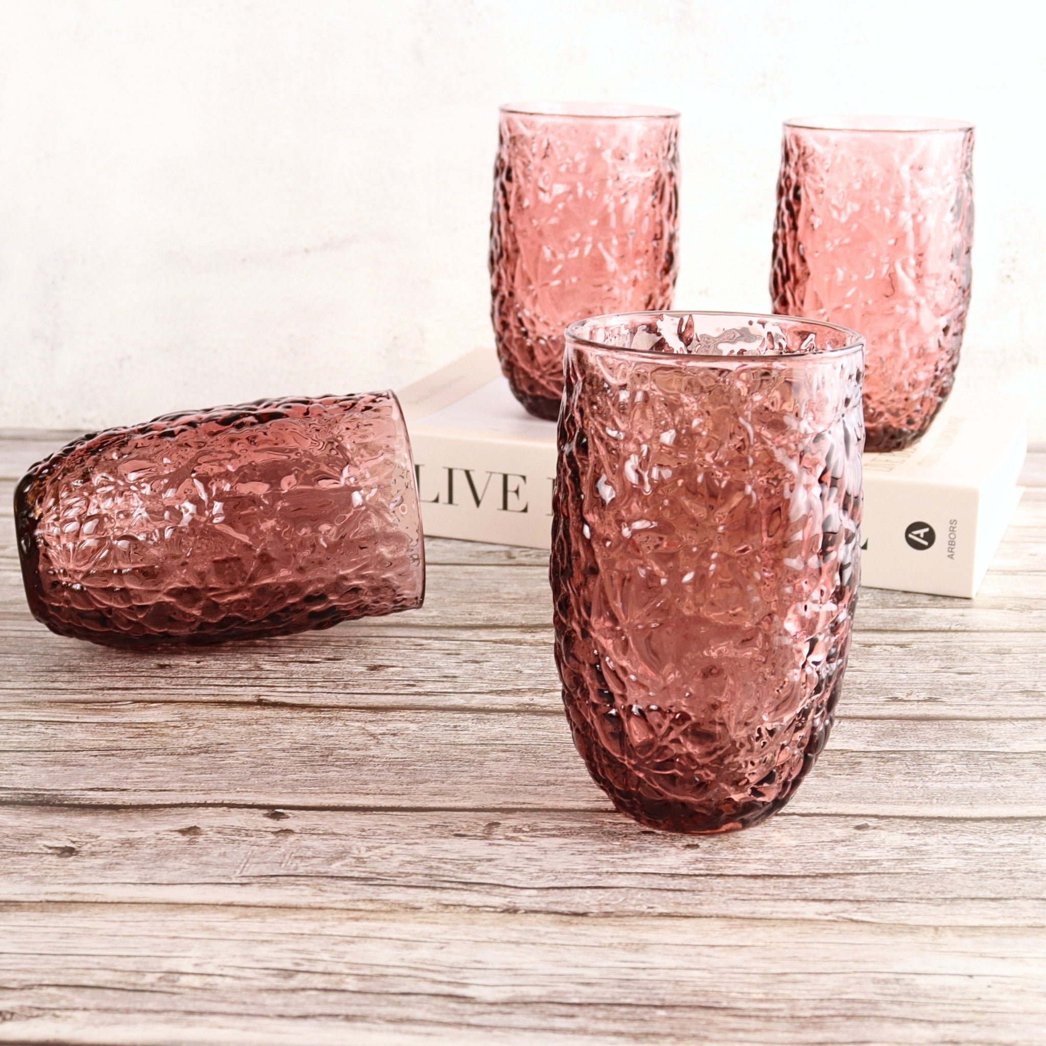 Set of pink textured glass tumblers on a wooden surface