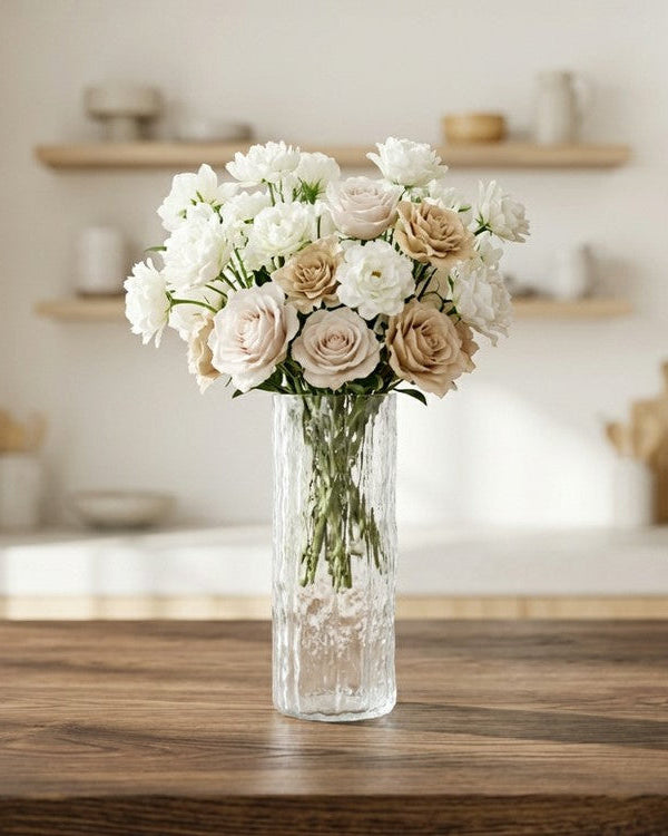 Clear glass vase with white flowers against a wooden background