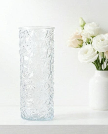 Decorative glass vase with white flowers against a wooden background
