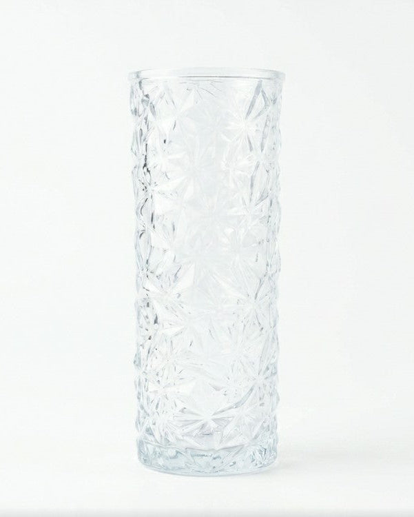Clear crystal vase with white flowers against a wooden background